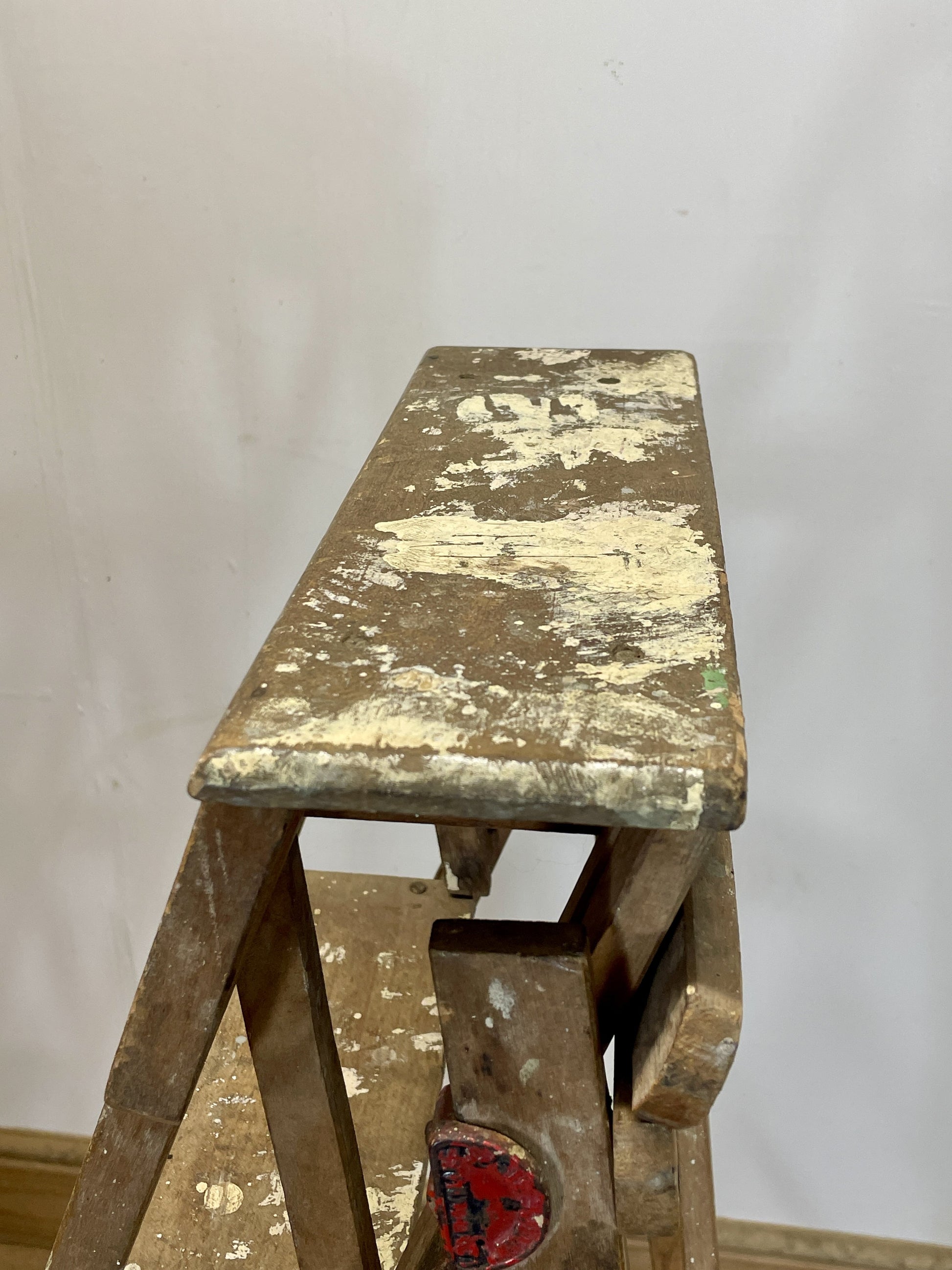 Wooden step ladder with peeling paint against a plain background