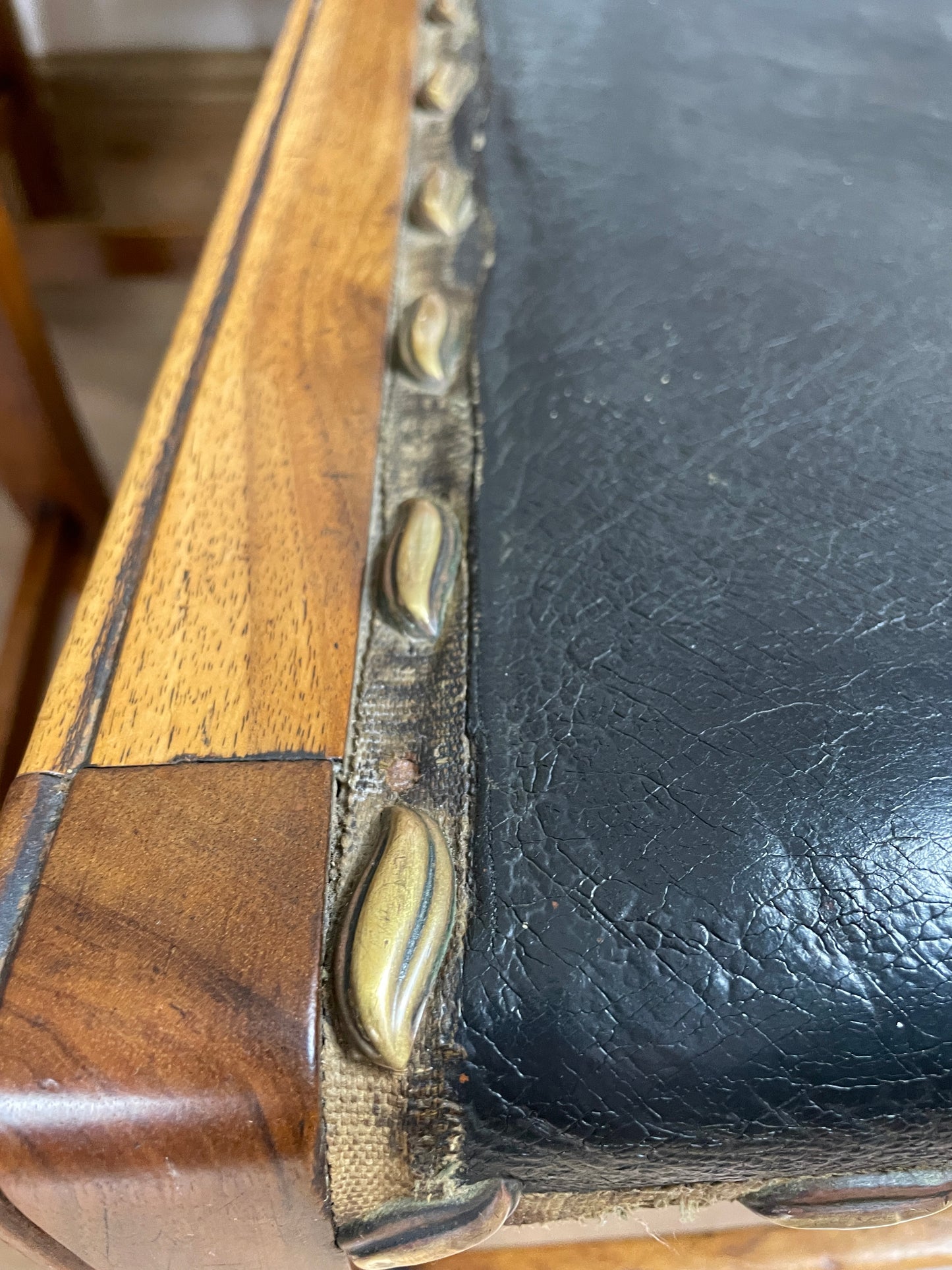 Close-up of a wooden and leather product with metal studs.