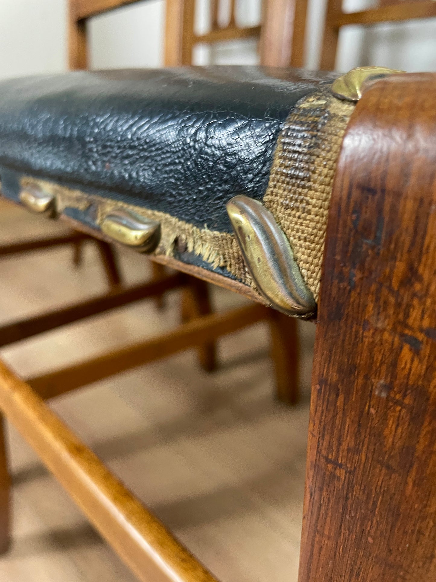 Close-up of a wooden chair with leather and brass trim