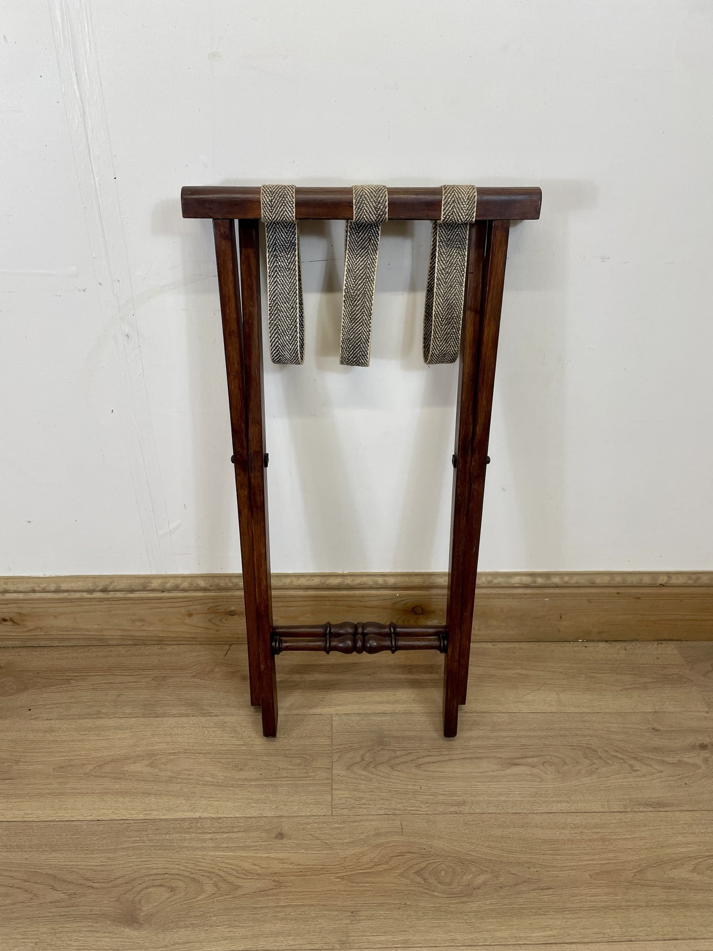 Wooden stand with woven top on a wooden floor against a white wall