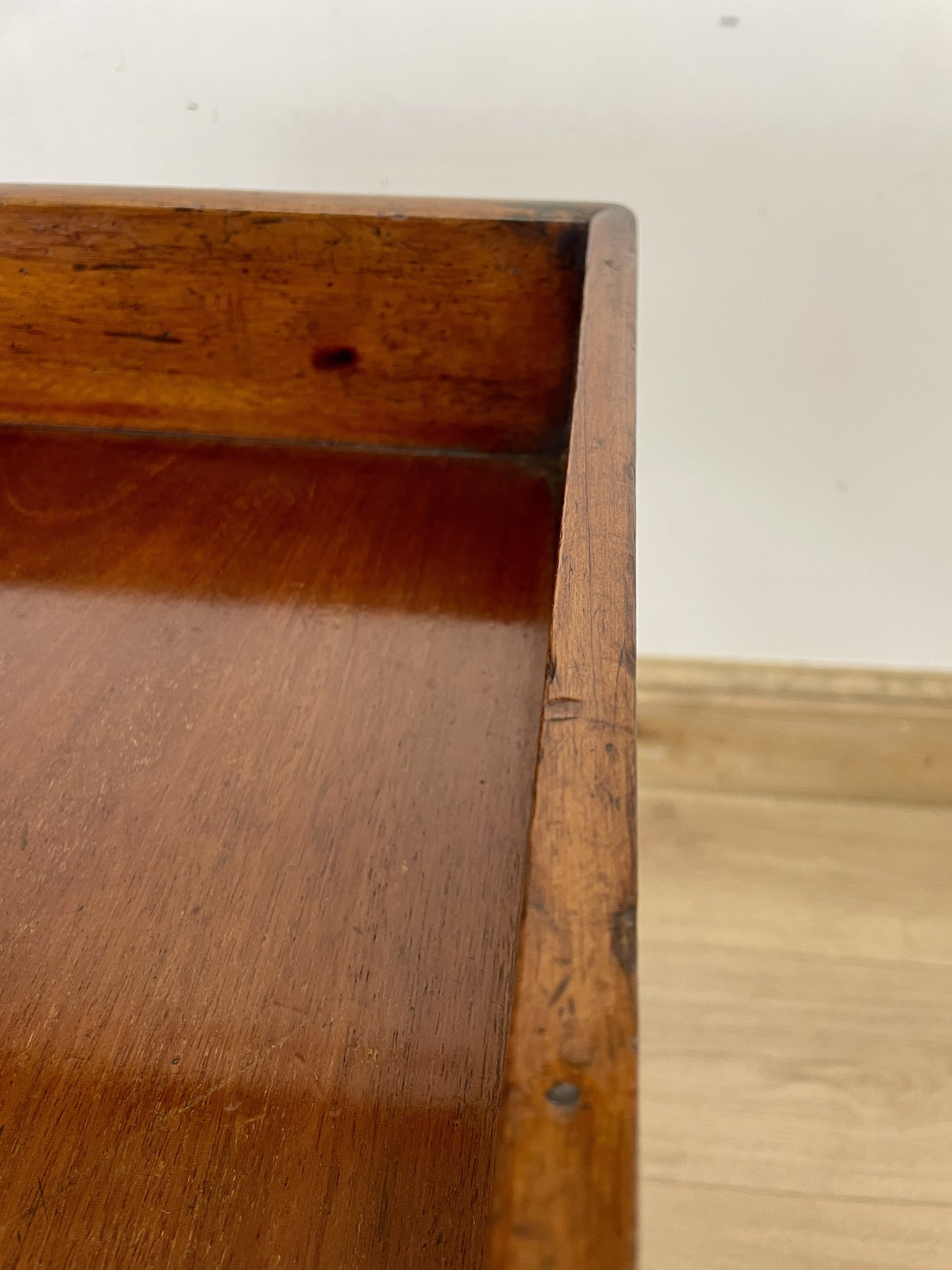 Close-up of a wooden shelf with a white wall background