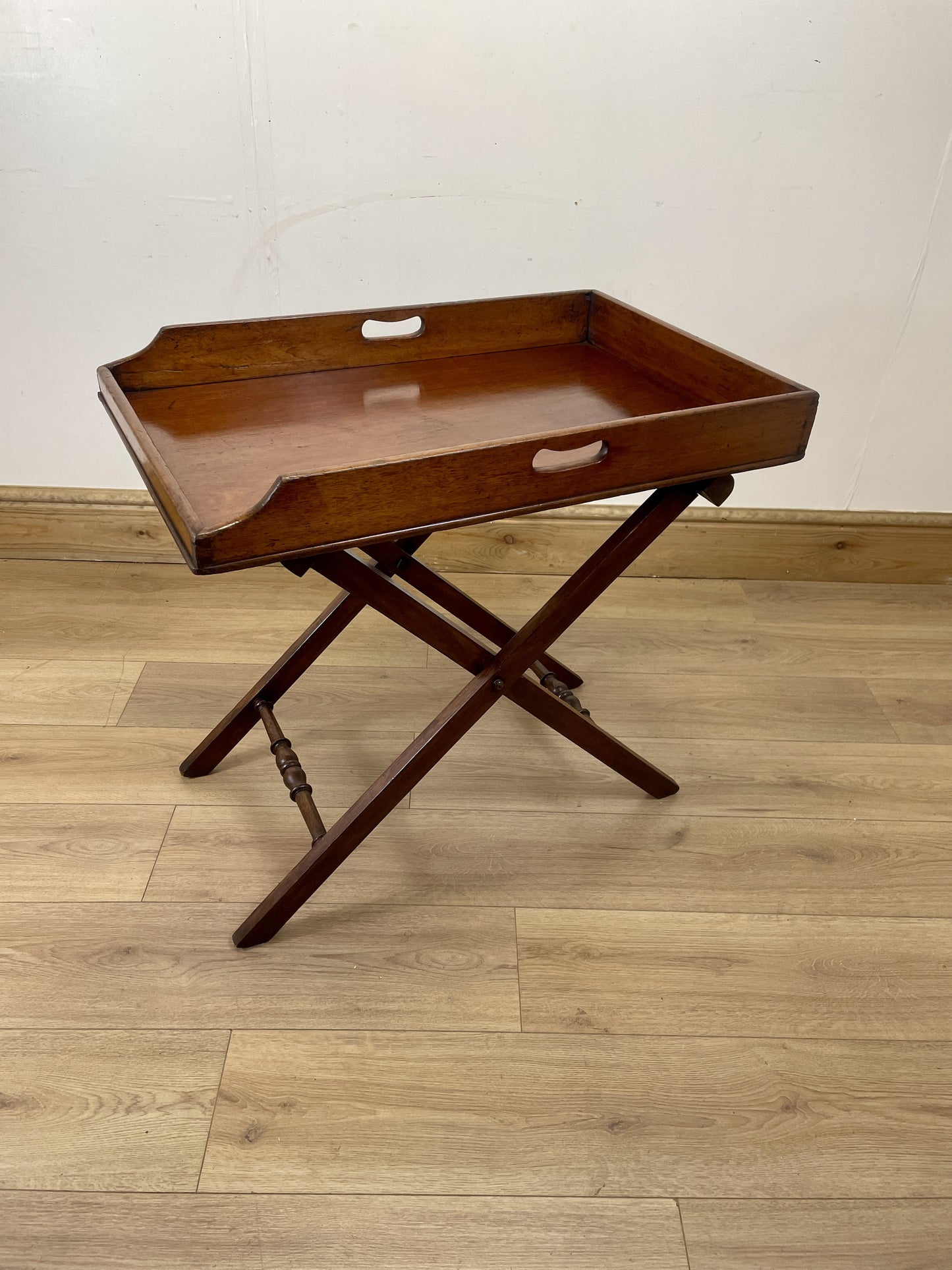 Wooden tray table on a wooden floor with a white wall background