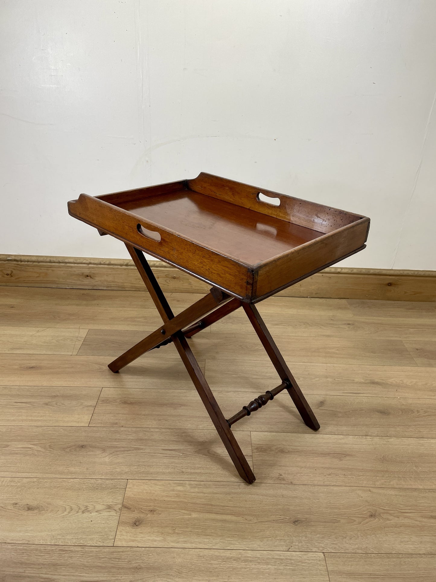 Wooden tray table on a wooden floor with a white wall background