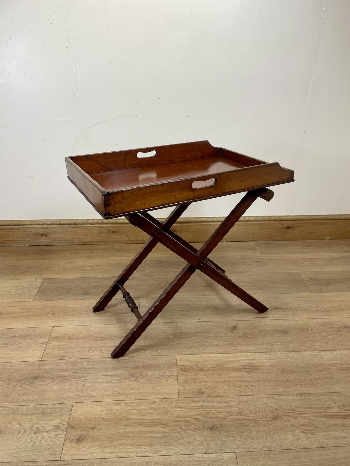 Wooden tray table on a wooden floor with a white wall background