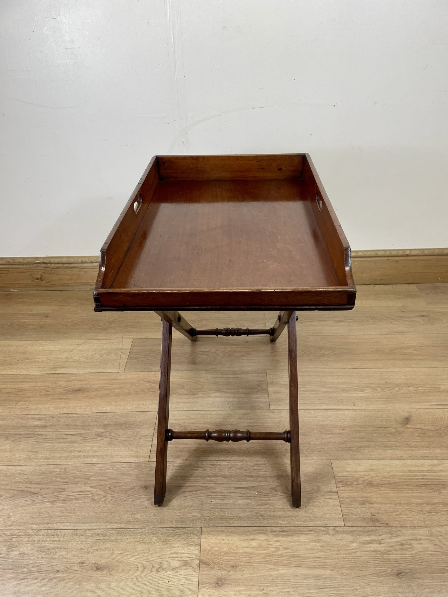 Wooden tray table on a wooden floor with a white wall background
