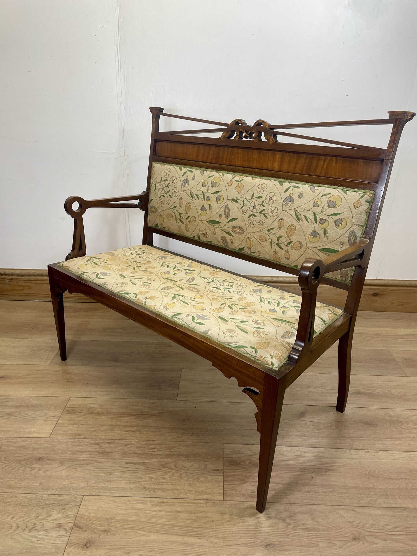 Wooden bench with floral-patterned cushions on a wooden floor.