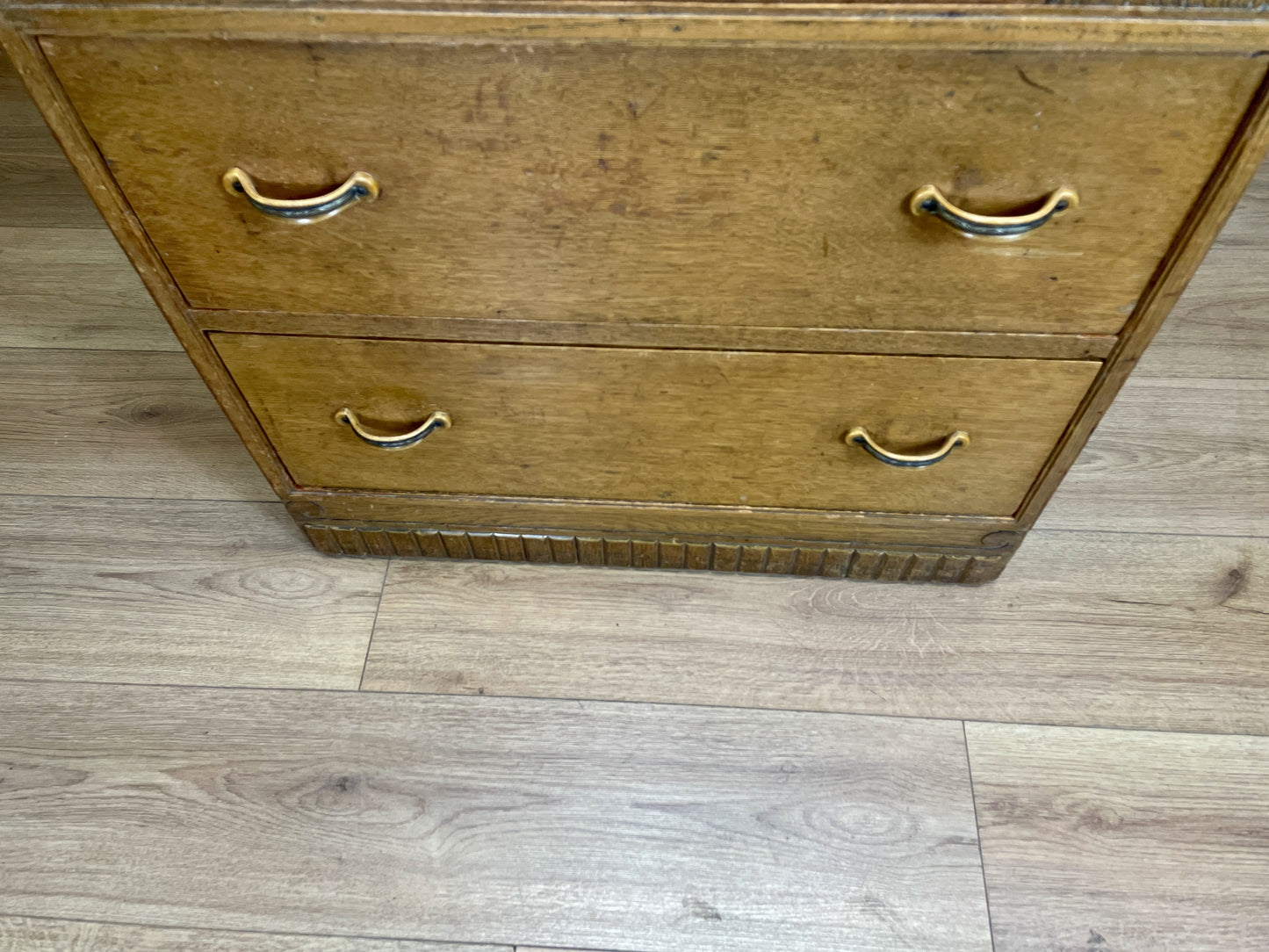 Wooden dresser with brass handles on a wooden floor