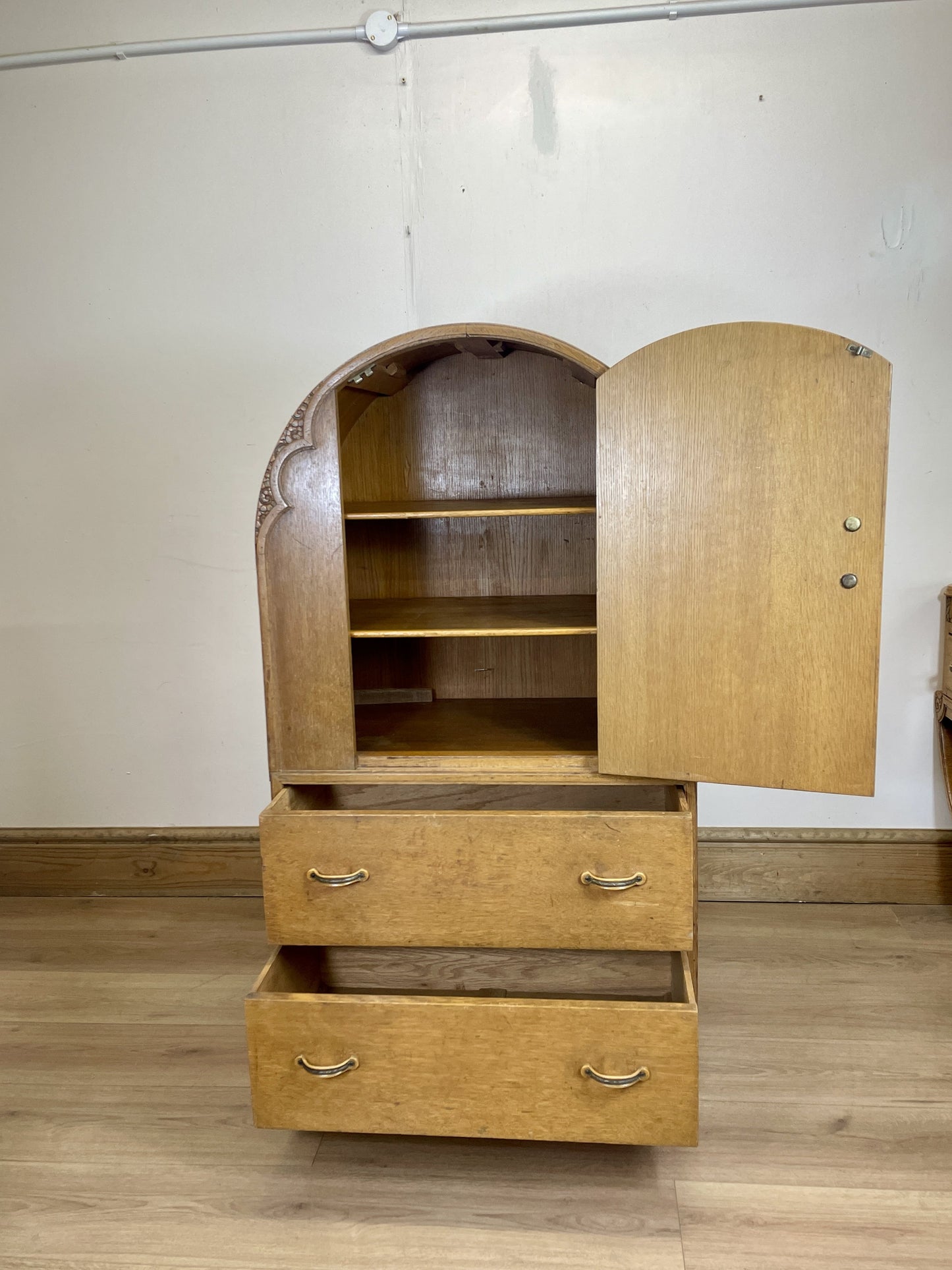 Wooden wardrobe with open doors on a wooden floor against a white wall