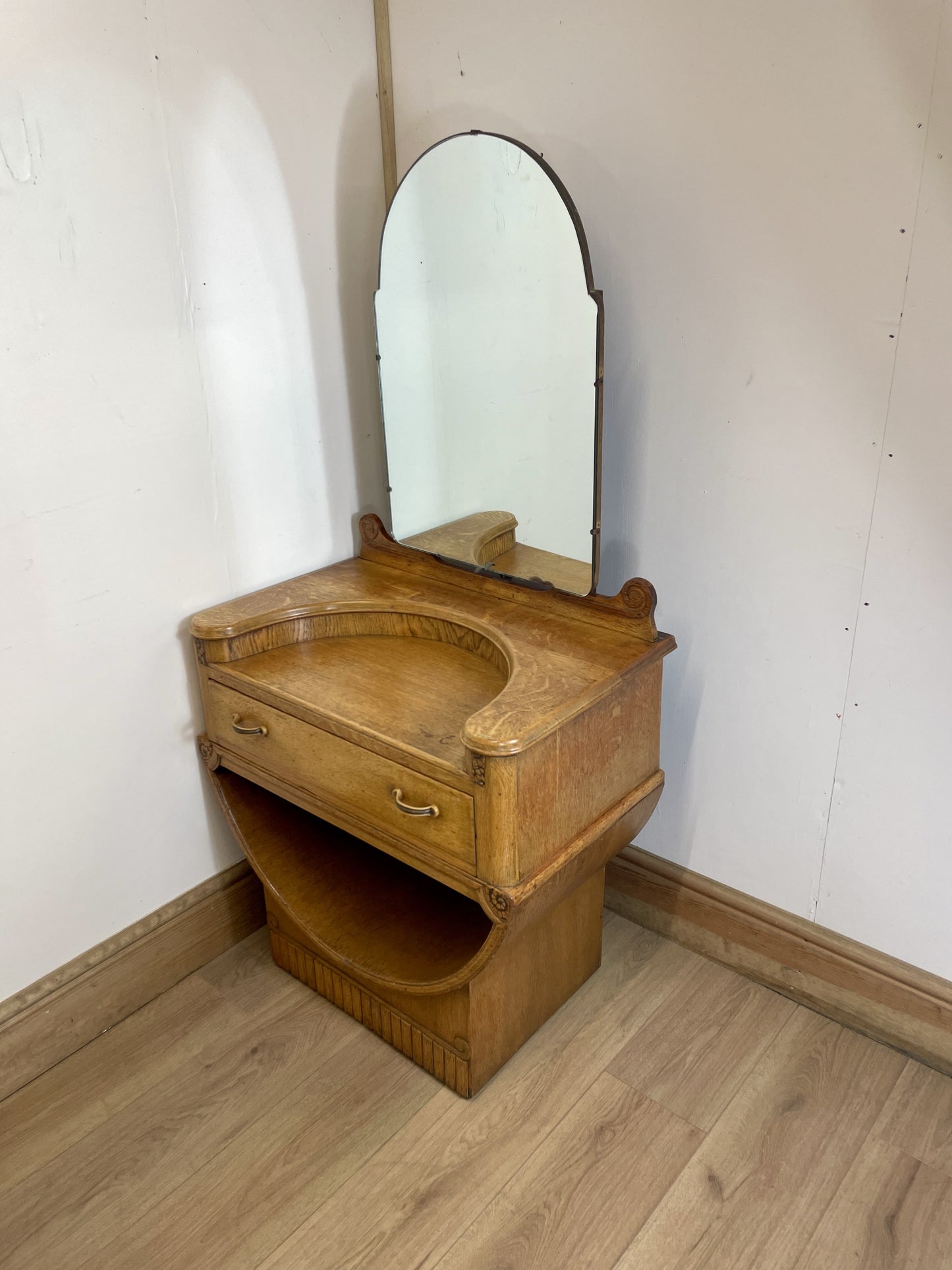 Wooden vanity with mirror against a white wall