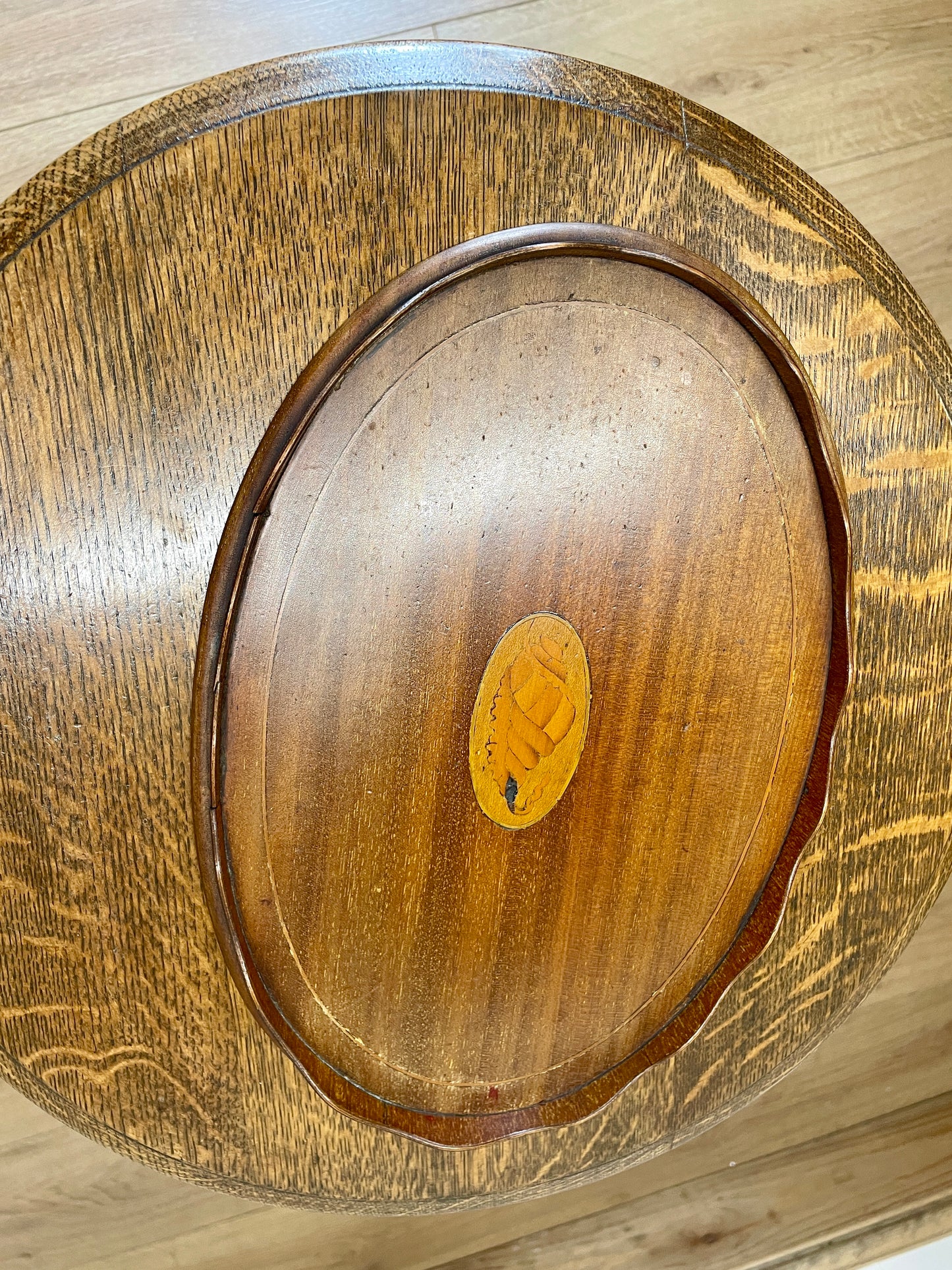 Wooden lid with a central emblem on a wooden surface