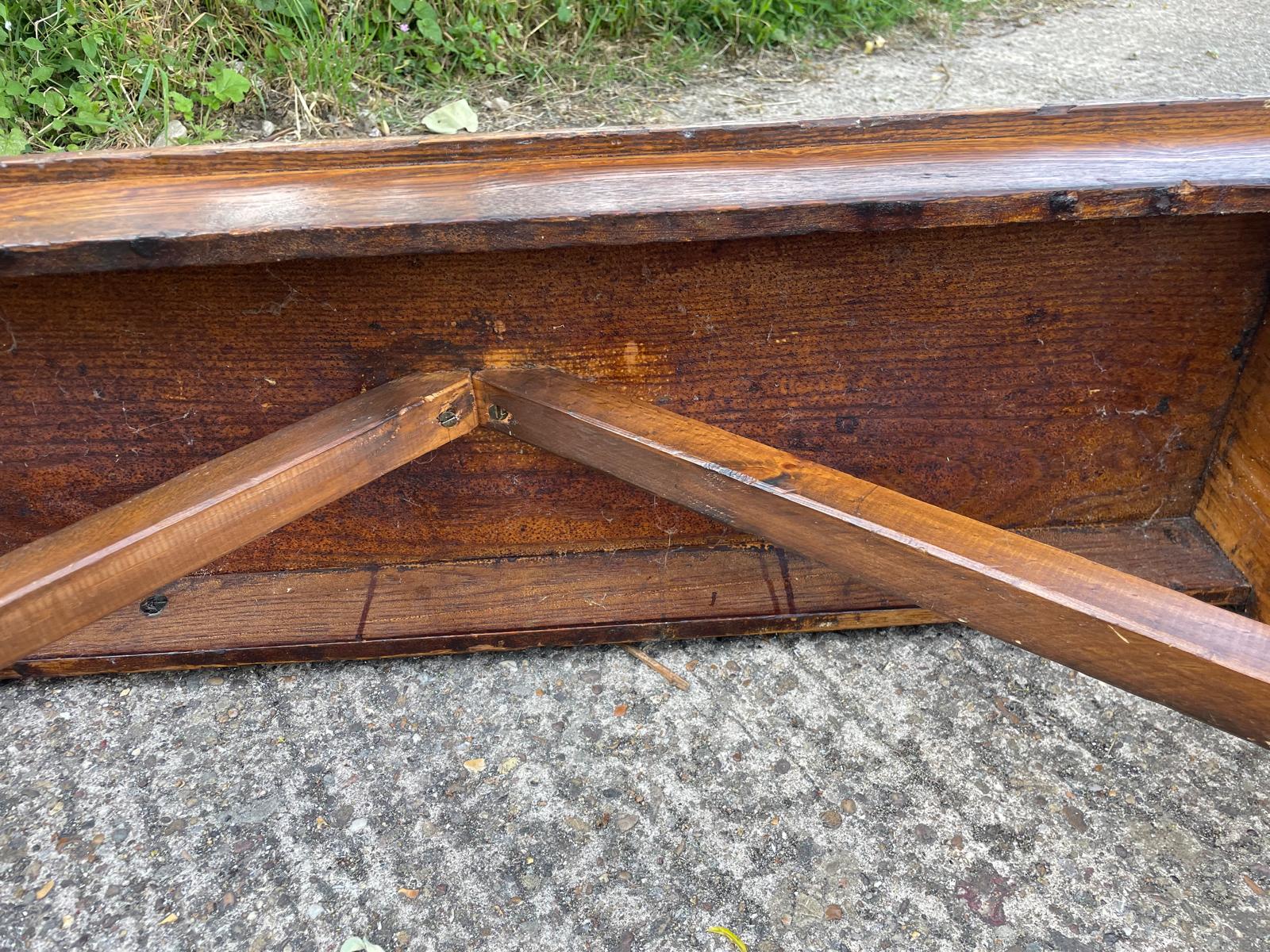Wooden bench with a broken armrest on a concrete surface