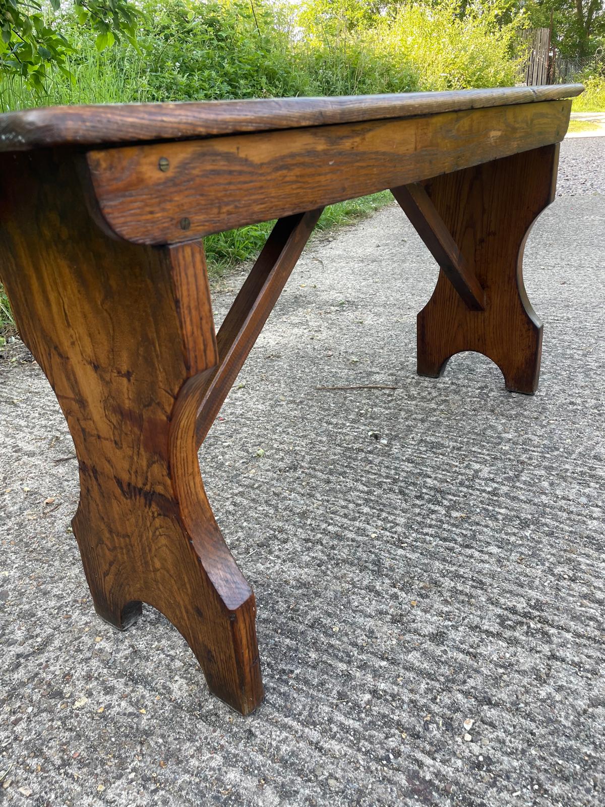 Wooden table with a rustic design on a concrete surface with grass in the background