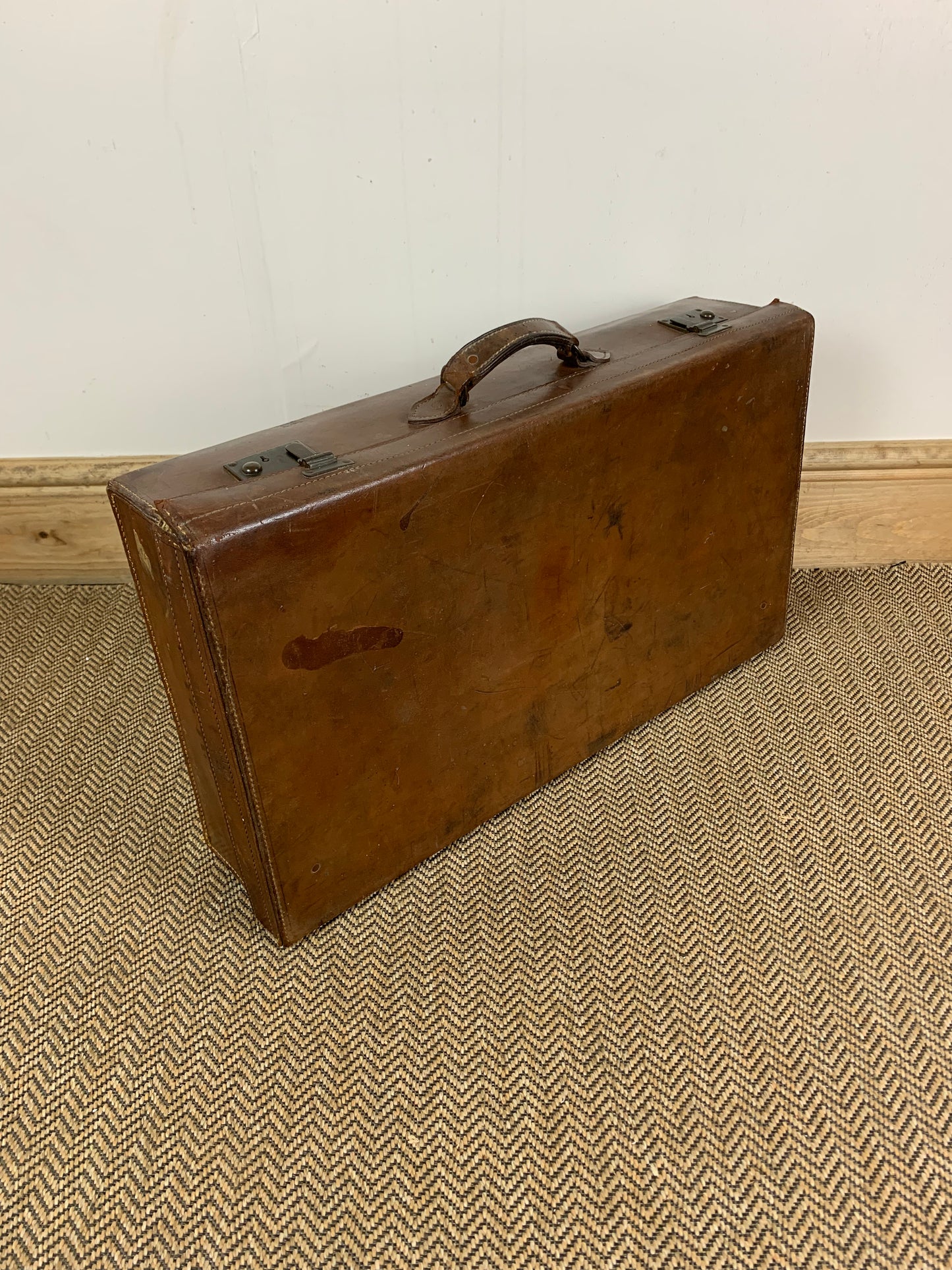 Vintage brown leather suitcase with a metal frame and a fabric handle.