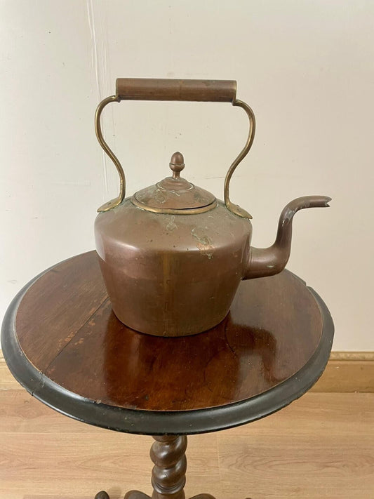 An 18th Century Antique Copper Kettle with a brass handle and spout, displayed on a wooden table.