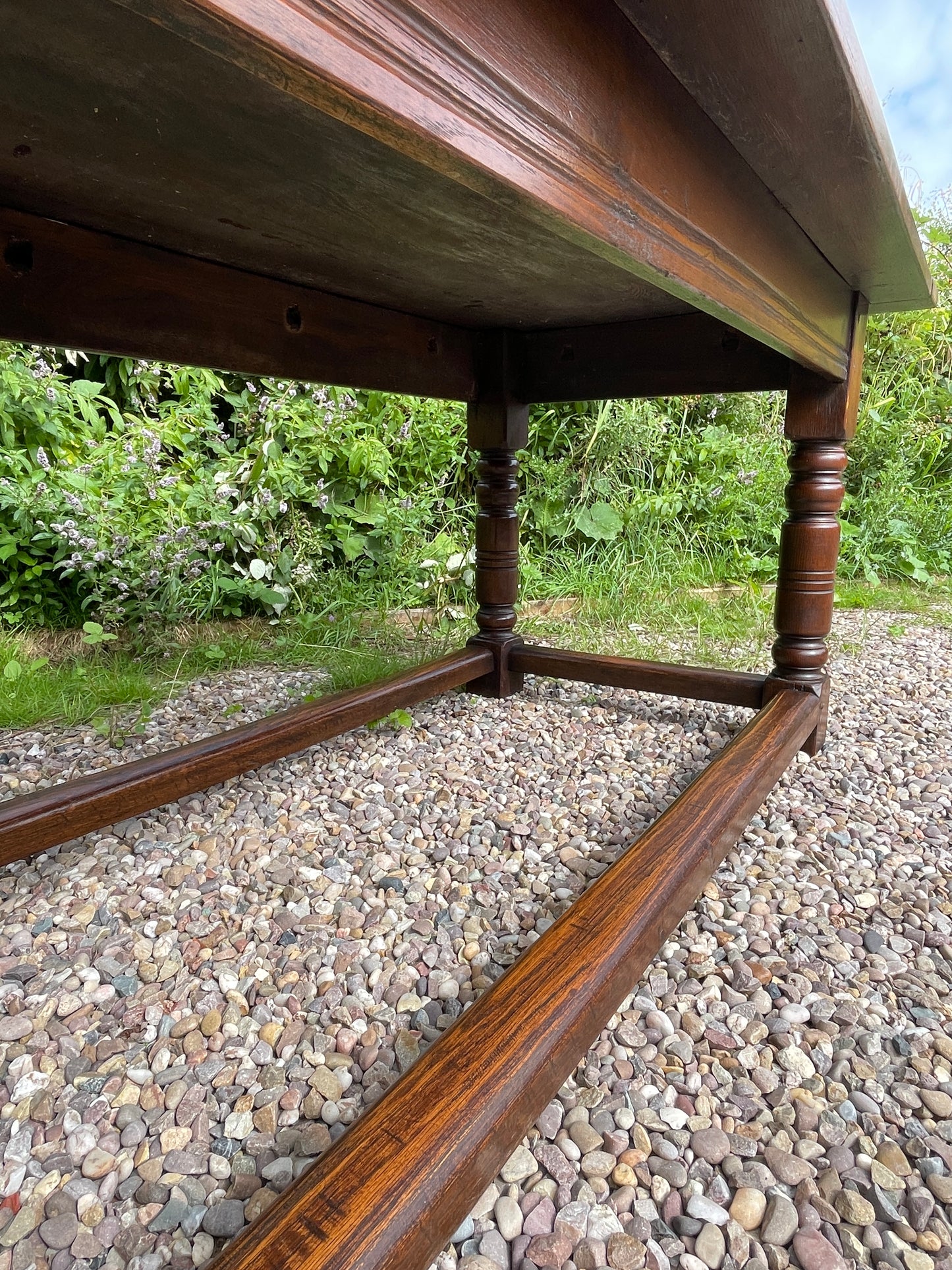 Wooden handrail on a pebbled path with greenery in the background