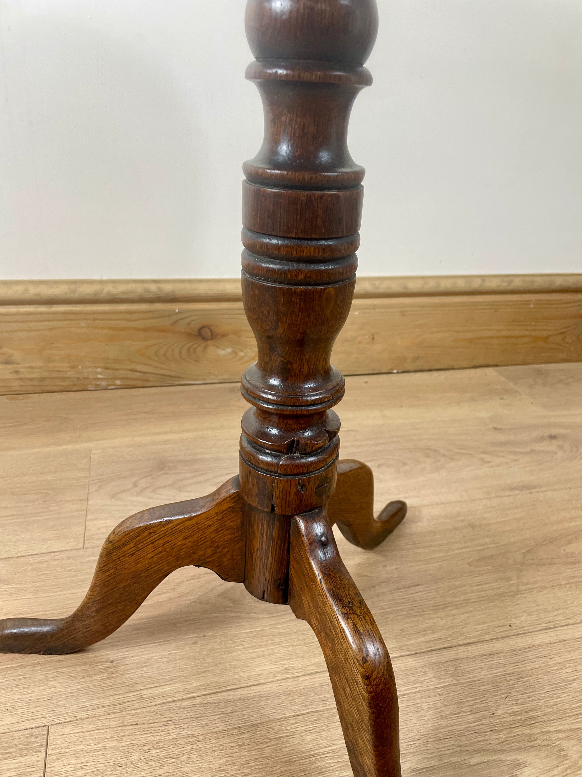 Wooden pedestal table base on a wooden floor