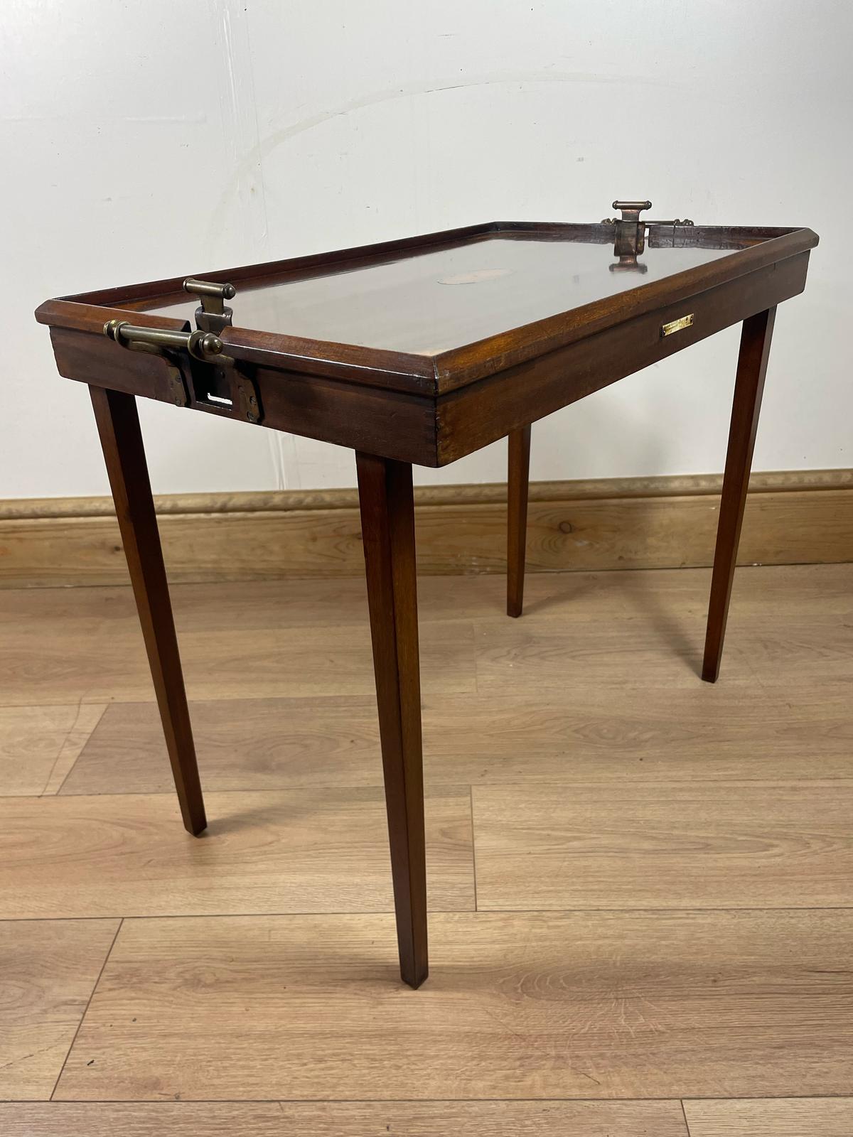 An Edwardian folding butler's table made of mahogany, standing on a wooden floor.