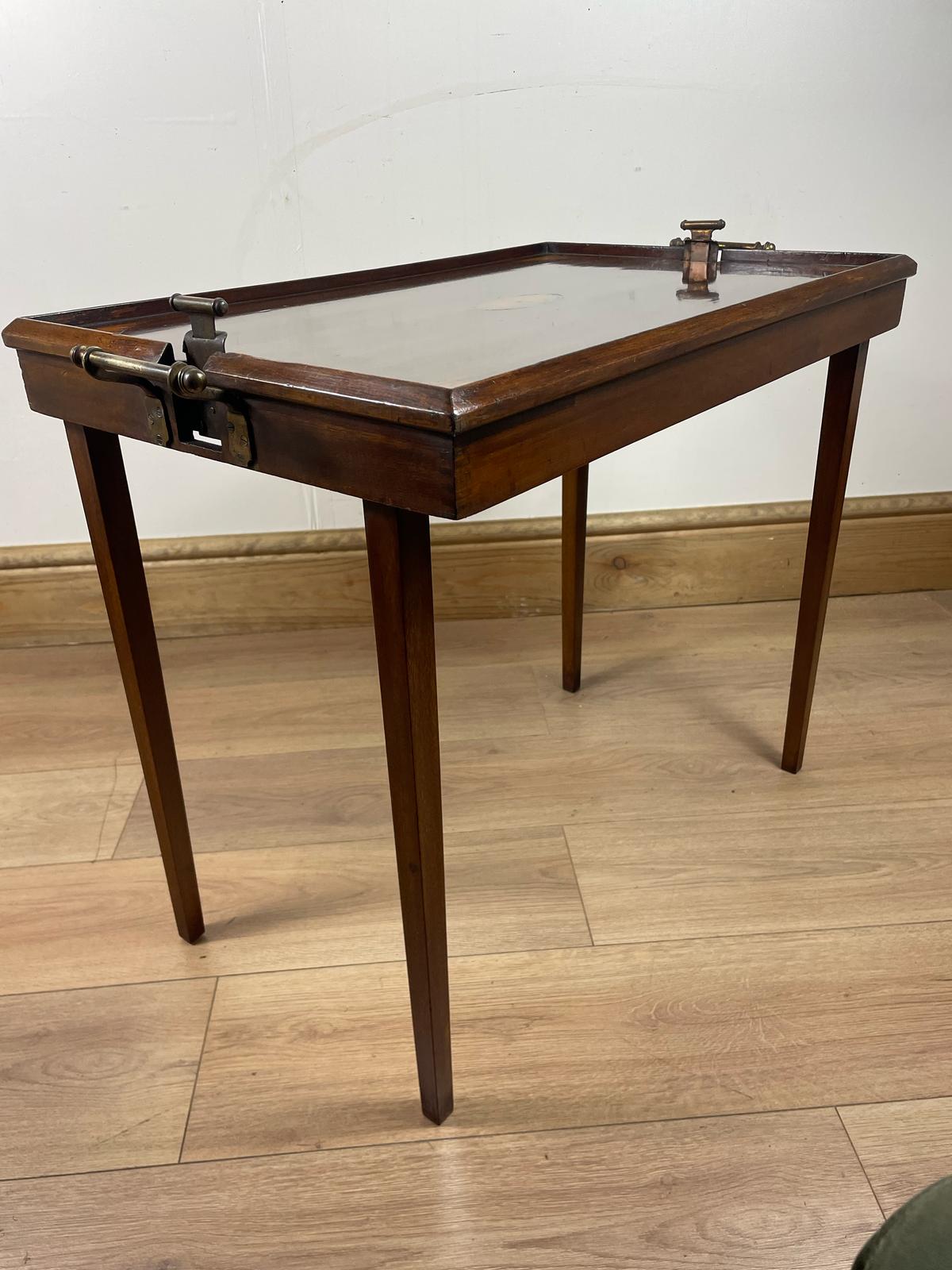 An Edwardian folding butler's table made of mahogany, standing on a wooden floor.