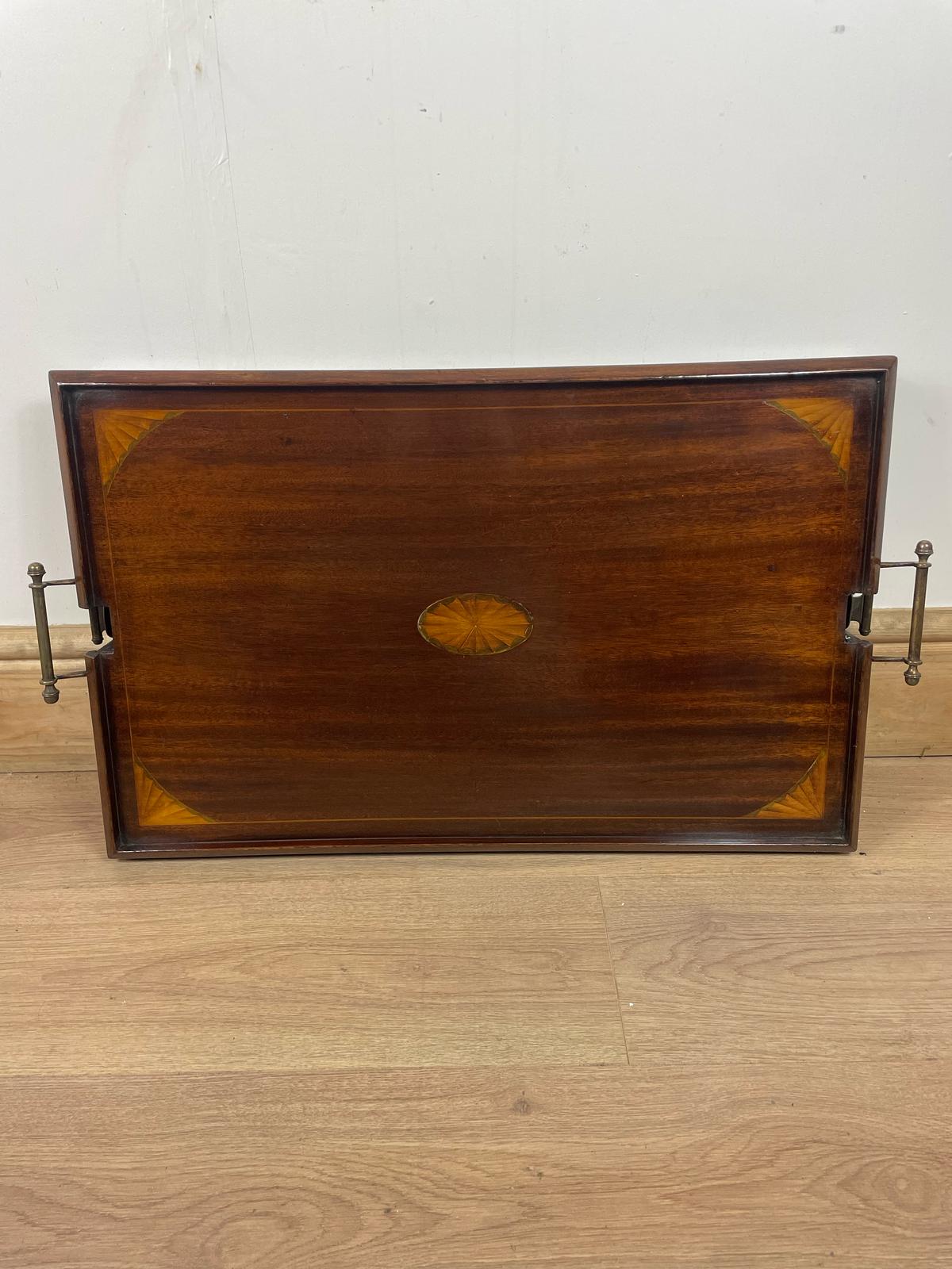 An Edwardian folding butler's table made of mahogany, standing on a wooden floor.