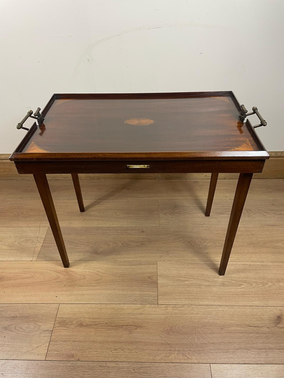 An Edwardian folding butler's table made of mahogany, standing on a wooden floor.