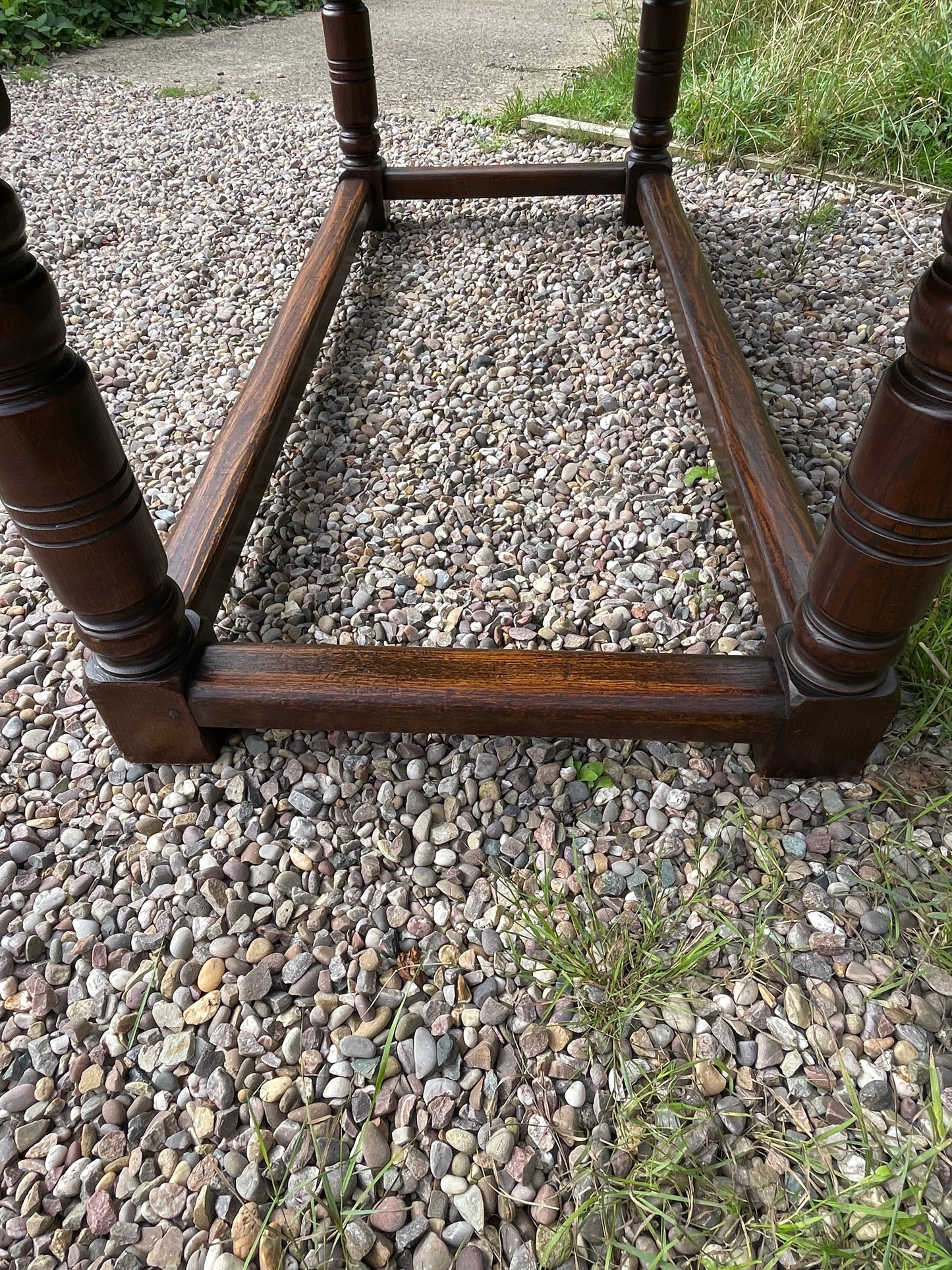 Brown metal stand on a gravel surface with grass in the background