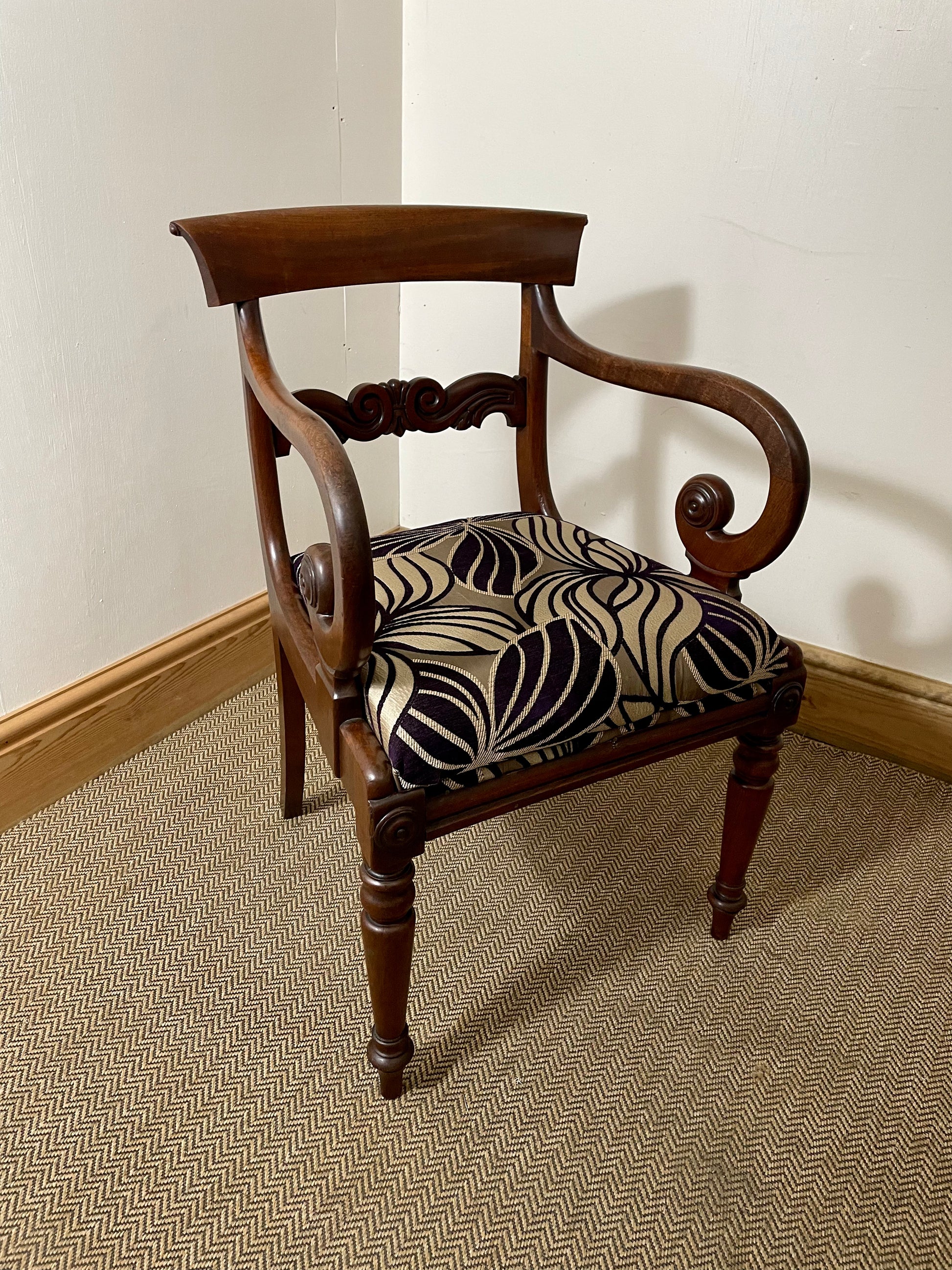 A Victorian Antique Scroll Arm Chair with a wooden frame and a patterned fabric seat cushion.