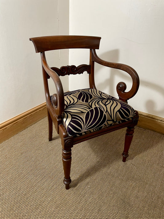 A Victorian Antique Scroll Arm Chair with a wooden frame and a patterned fabric seat cushion.
