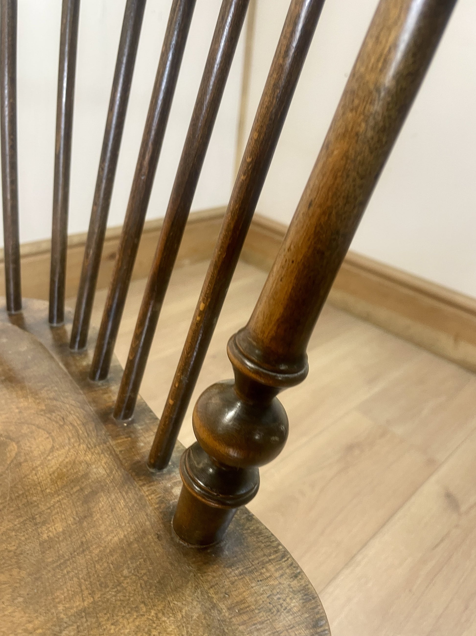 Close-up of a wooden chair with wooden legs on a wooden floor.