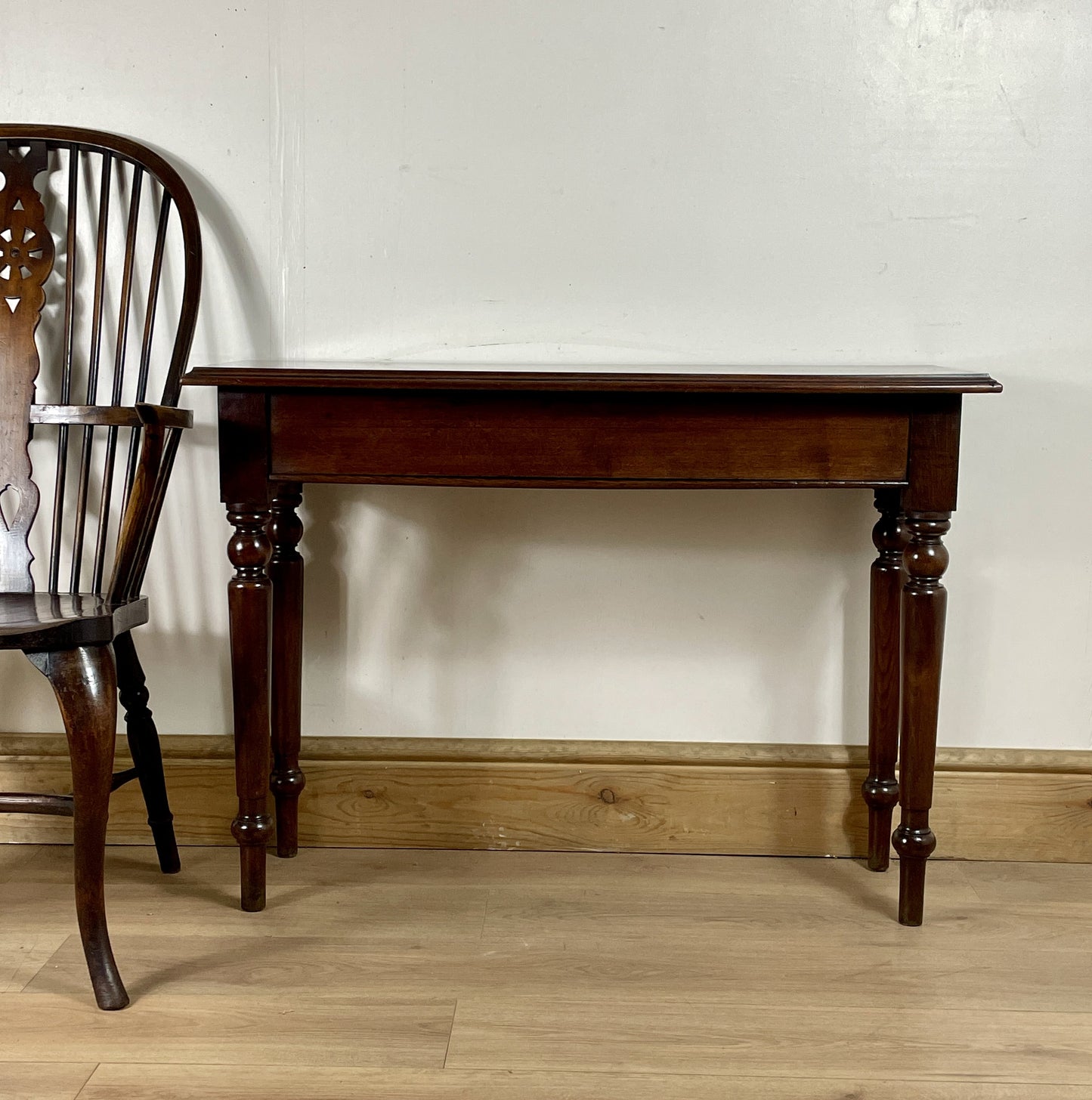 Wooden table and chair against a white wall on a wooden floor
