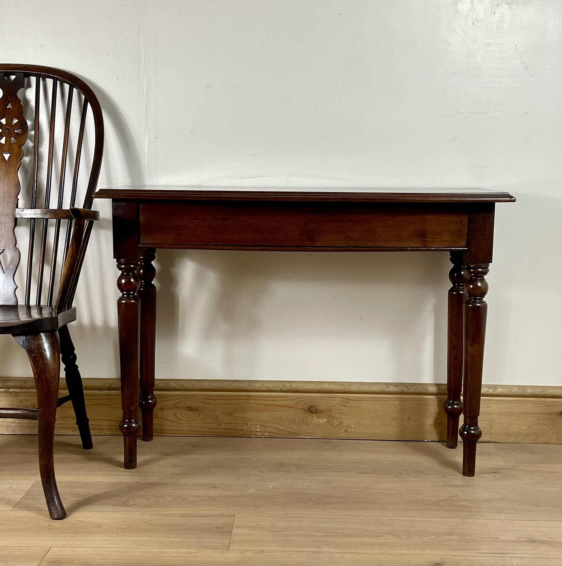 Wooden table and chair against a white wall on a wooden floor