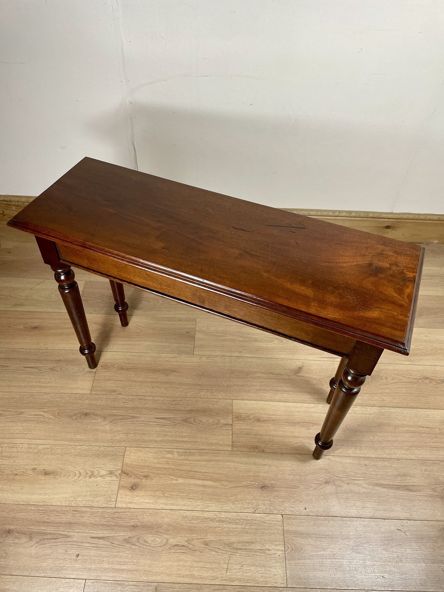 Wooden table on a wooden floor with a plain wall background