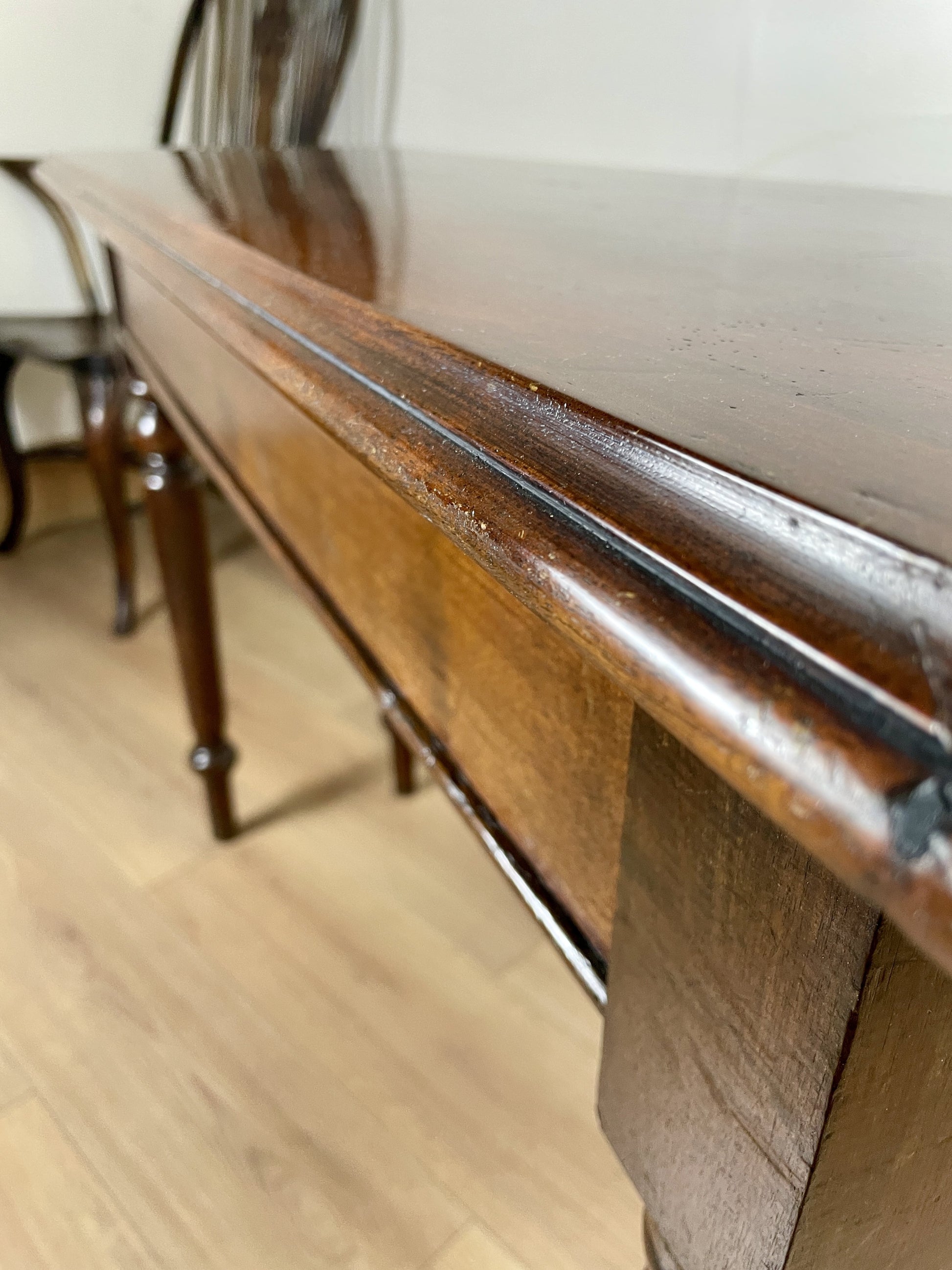 Close-up of a wooden piano with a metal bar on a light wood floor.