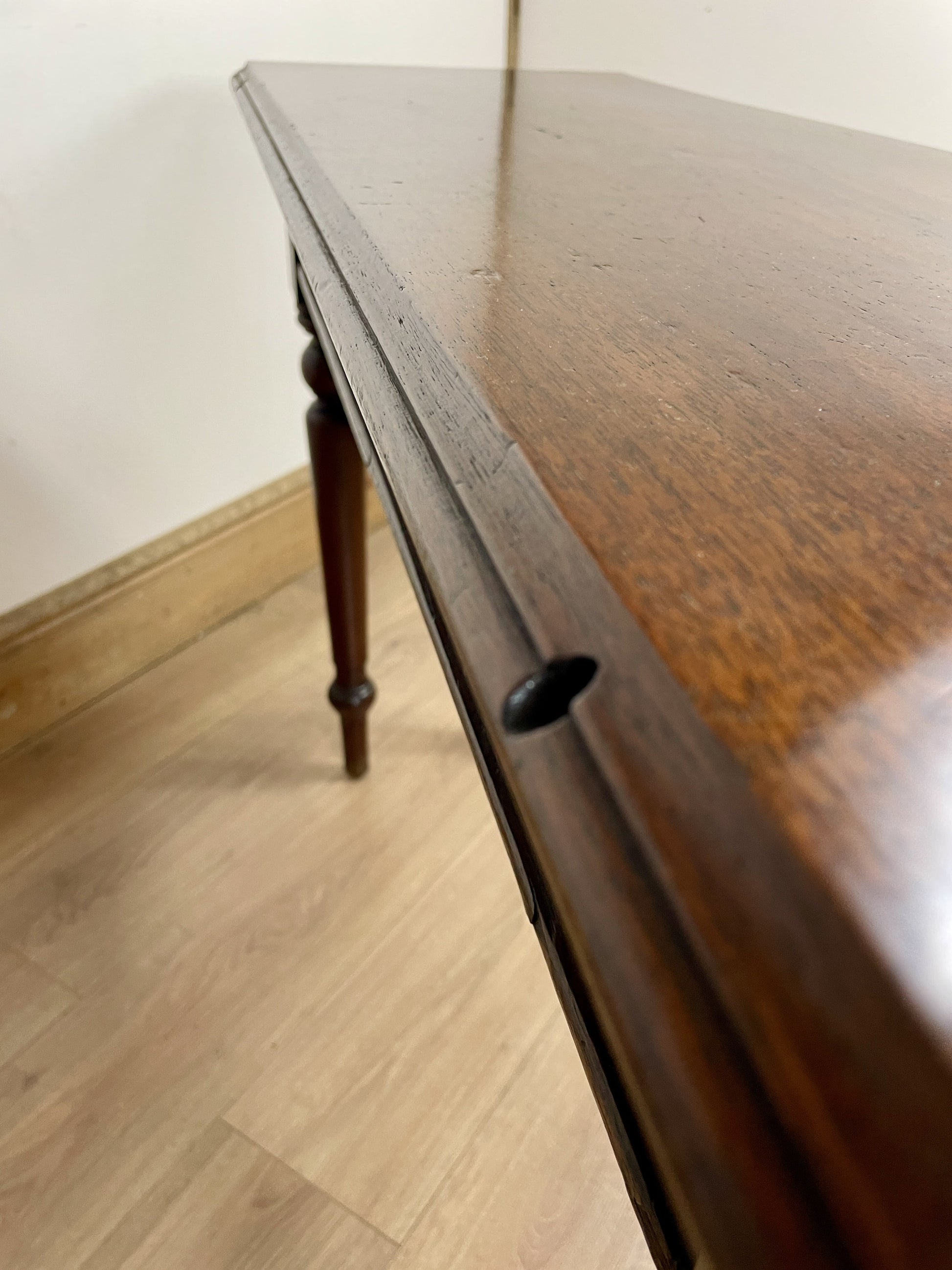 Wooden desk with a worn surface on a wooden floor.