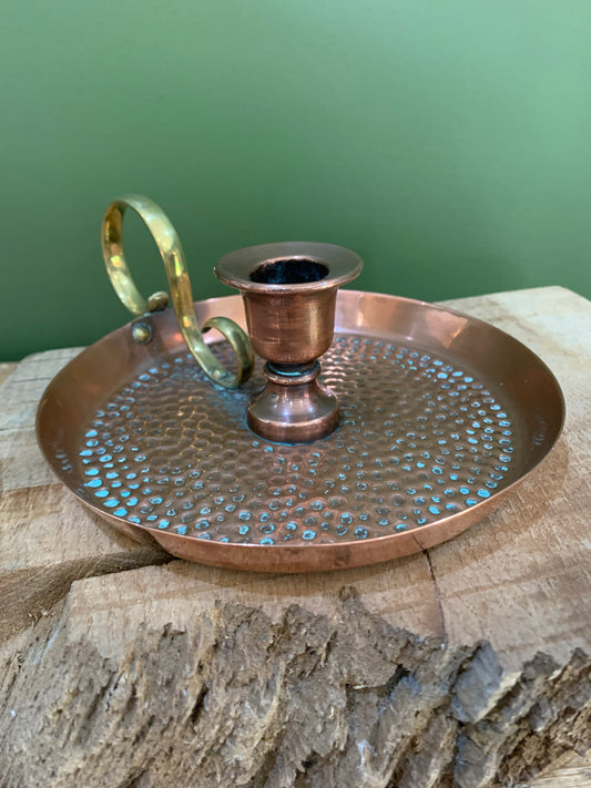 Antique copper and brass candle holder with a hammered texture, displayed on a wooden surface.