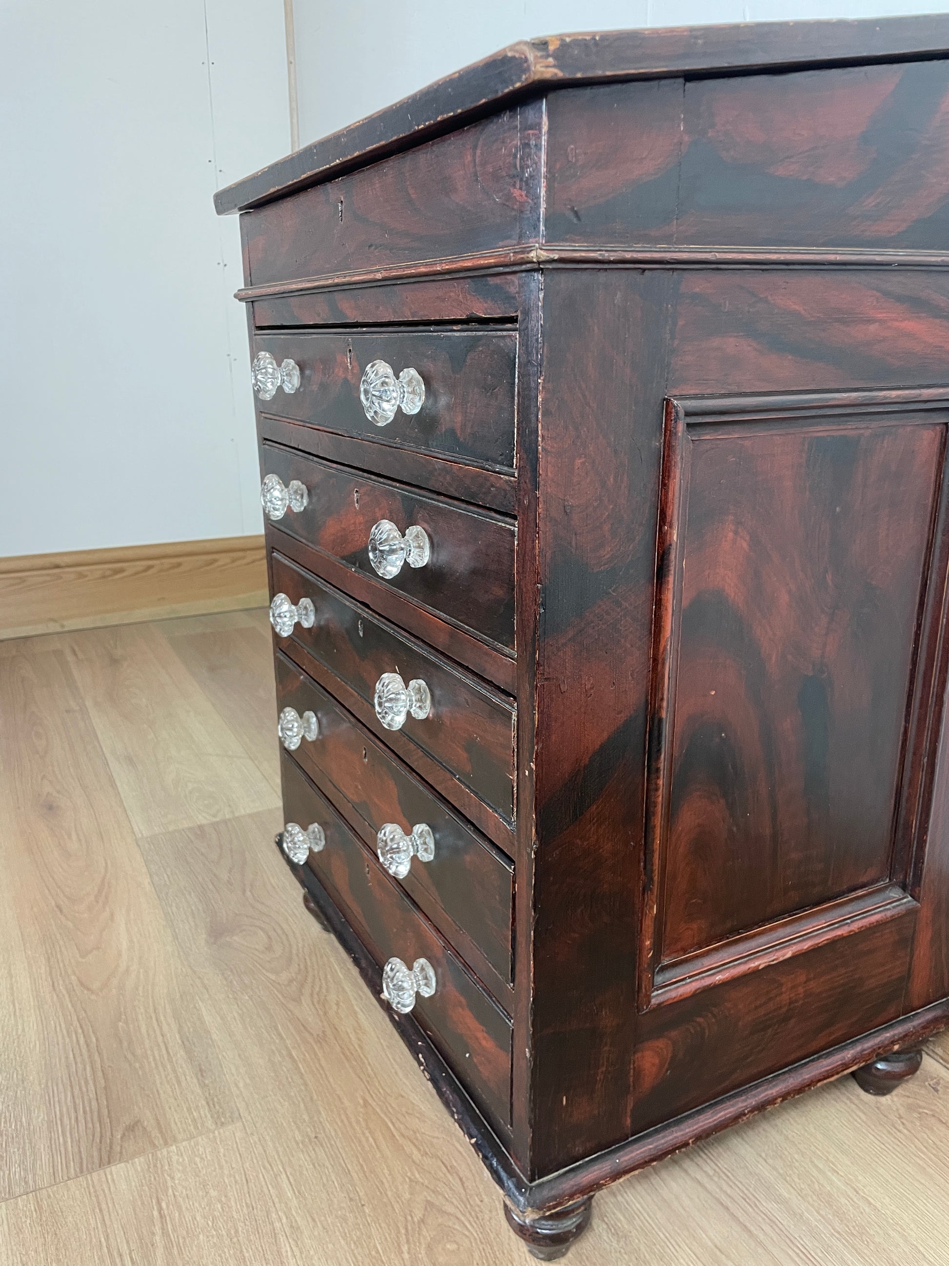Wooden cabinet with glass panels and silver knobs on a wooden floor.