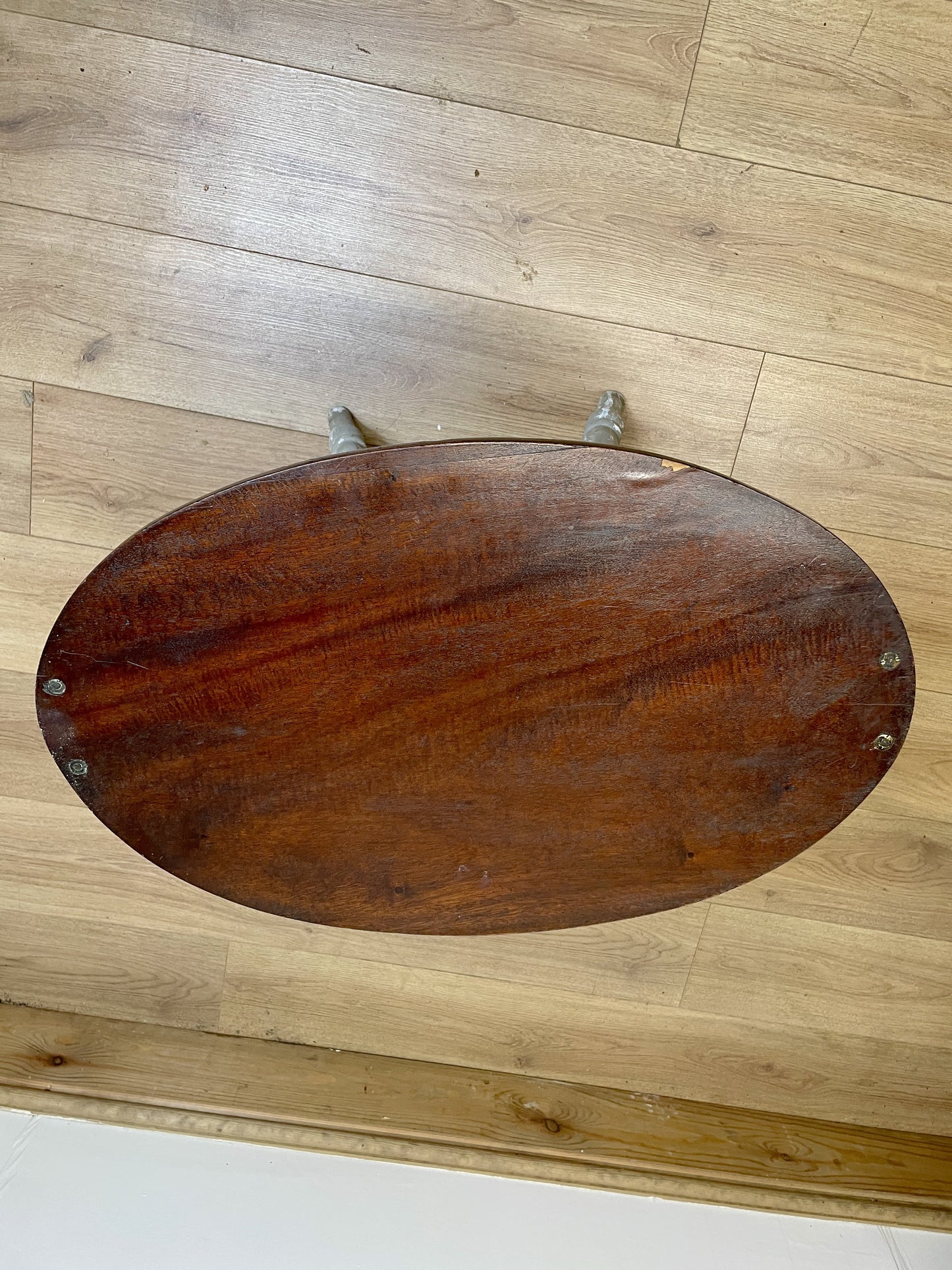 Wooden stool with a dark brown seat on a wooden floor