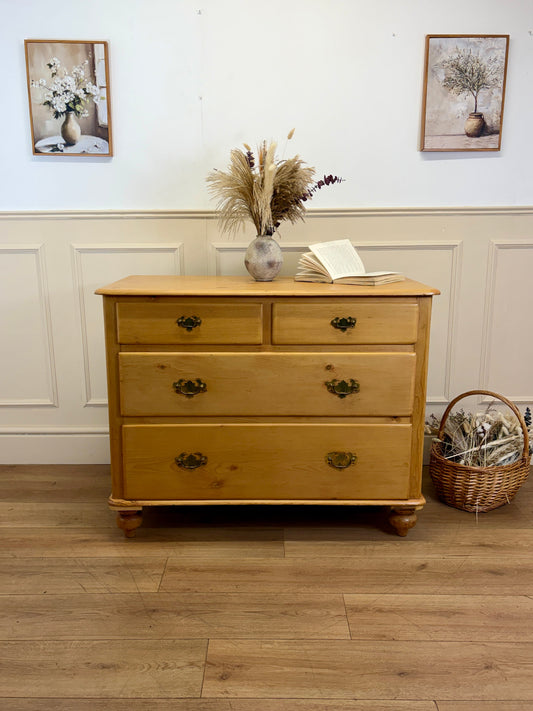 Wooden dresser with decorative items on a wooden floor against a white wall.