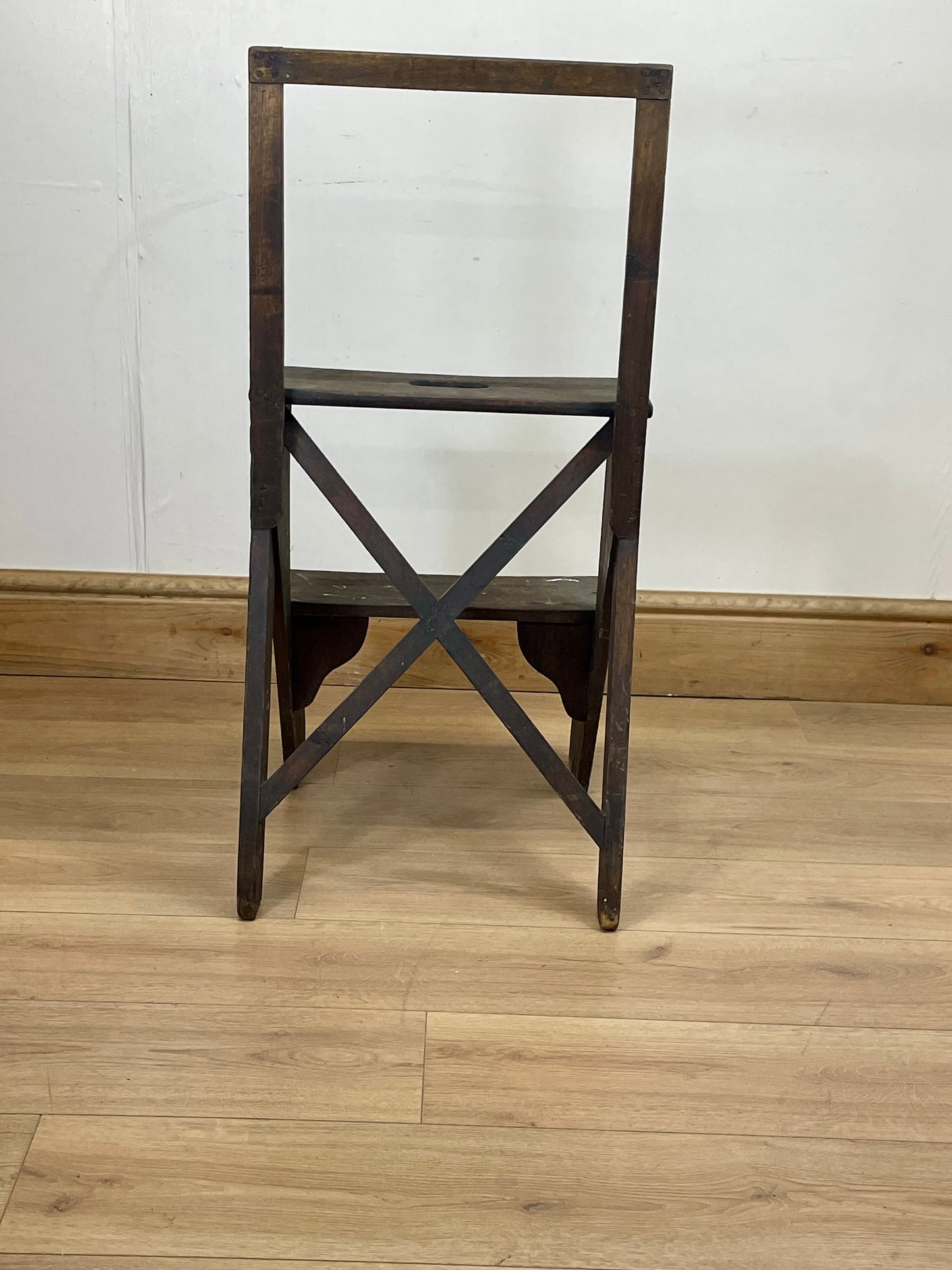 Wooden chair with a cross-back design on a wooden floor.