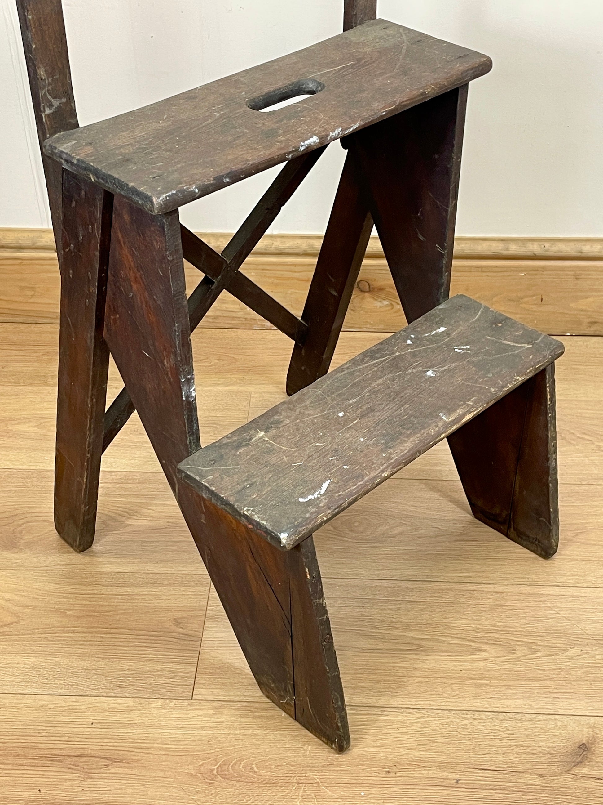 Wooden step ladder on a wooden floor with a white wall background