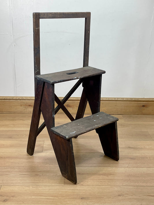 Wooden step ladder on a wooden floor with a white wall background