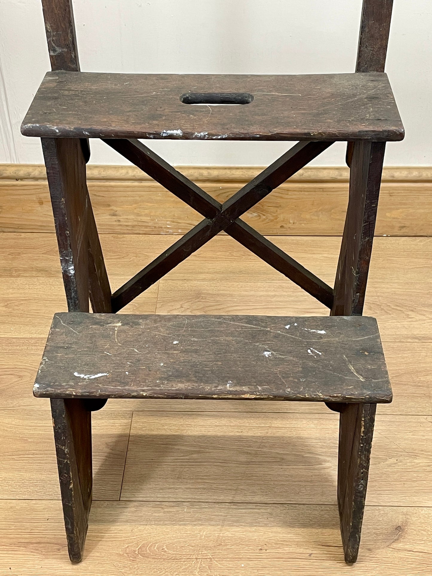 Wooden step stool with two platforms on a wooden floor.