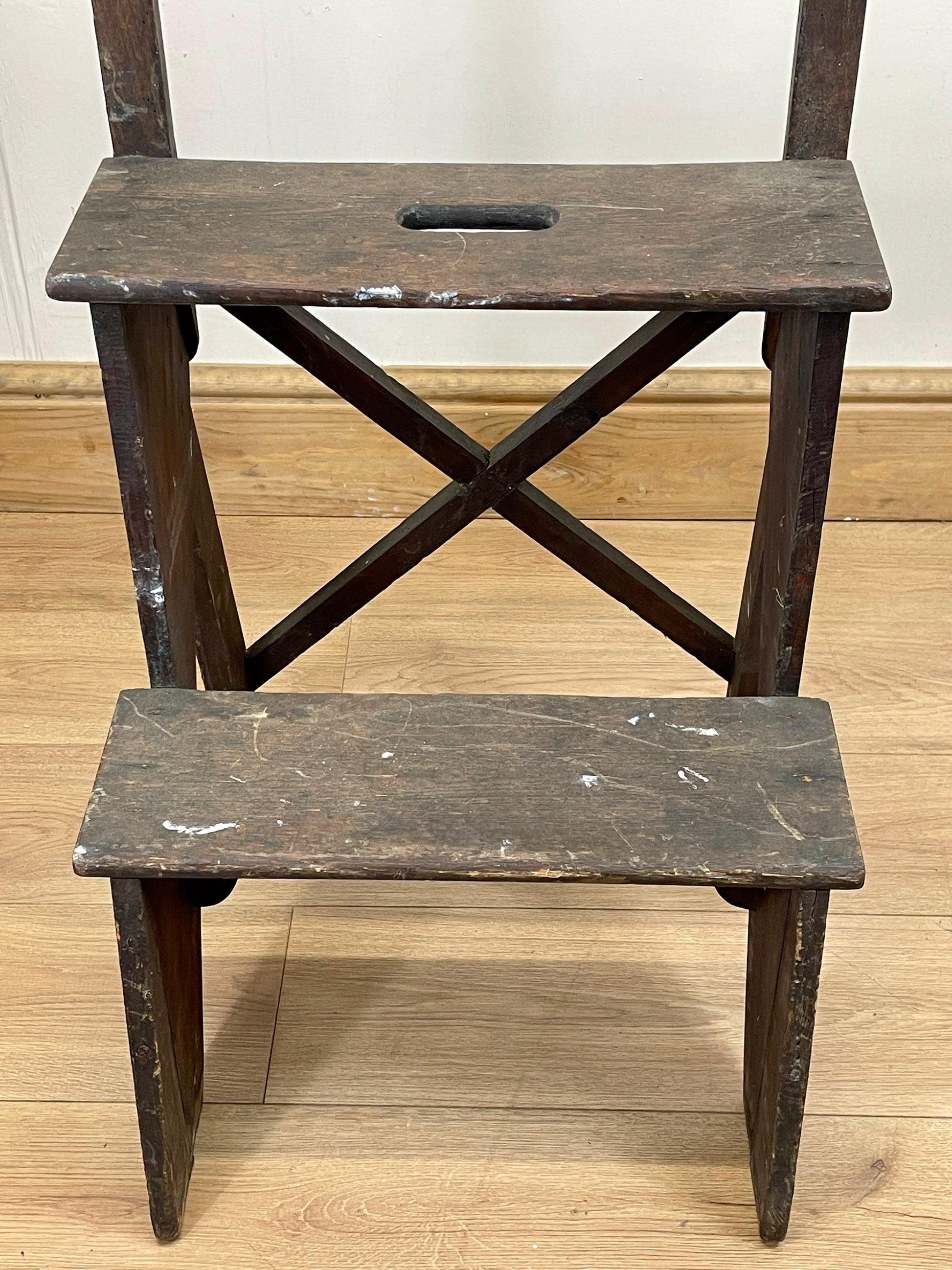 Wooden step stool with two platforms on a wooden floor.
