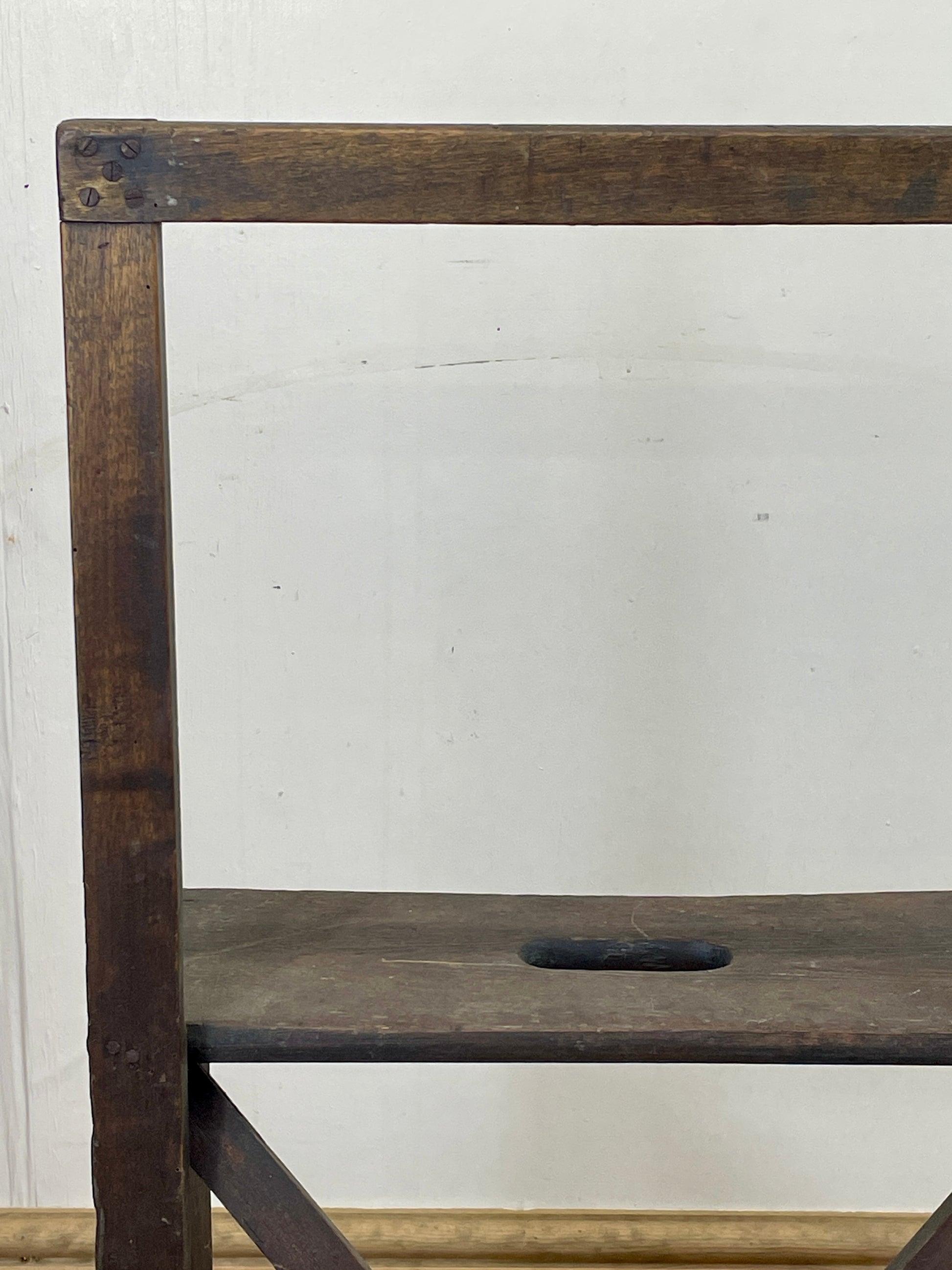 Wooden chair with a worn finish against a plain white wall