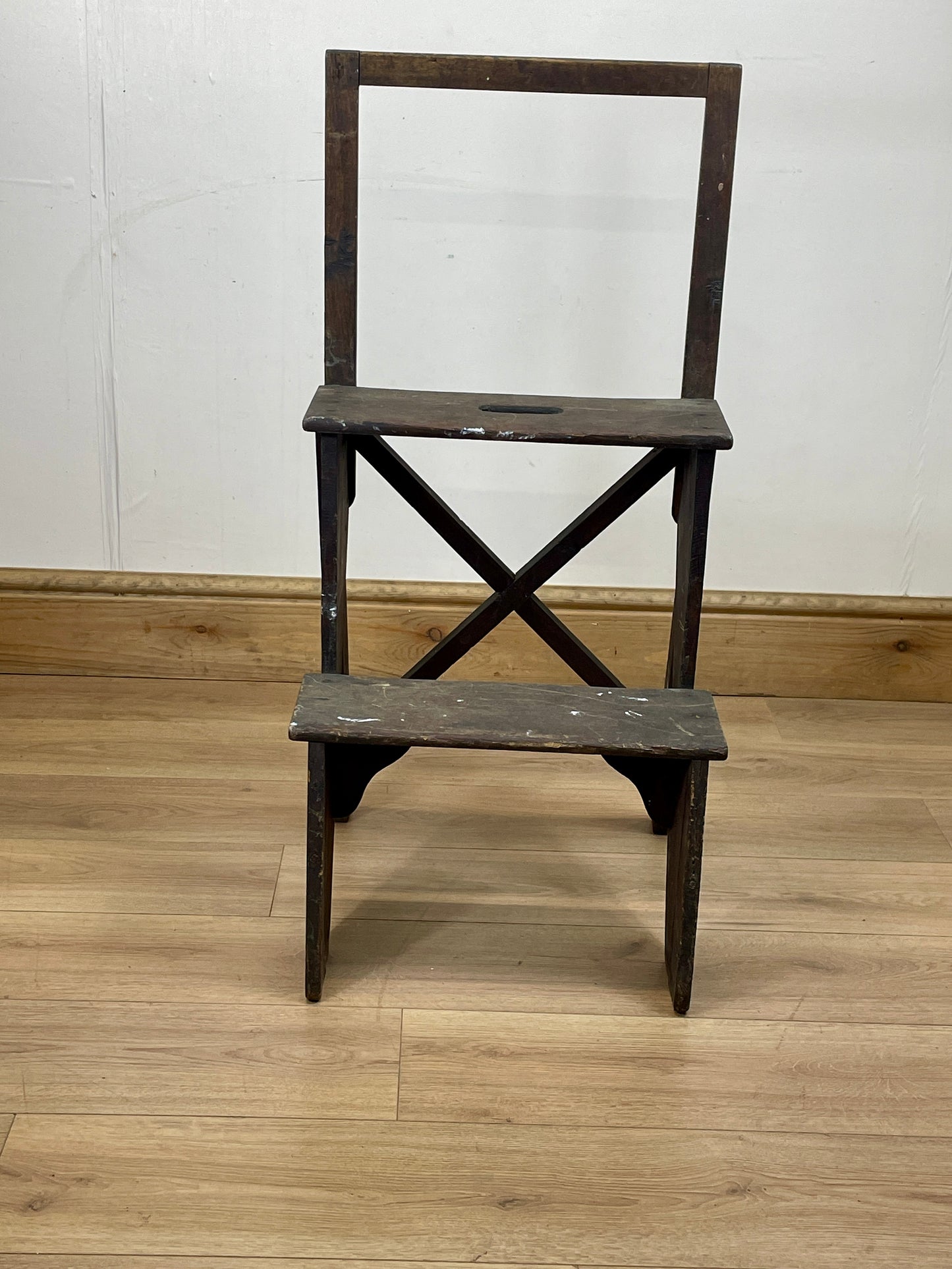 Wooden step stool with a white wall and wooden floor background
