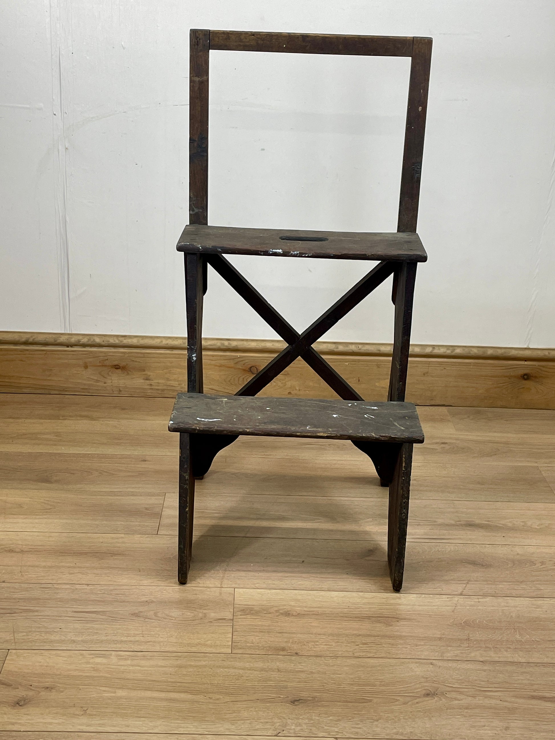 Wooden step stool with a white wall and wooden floor background