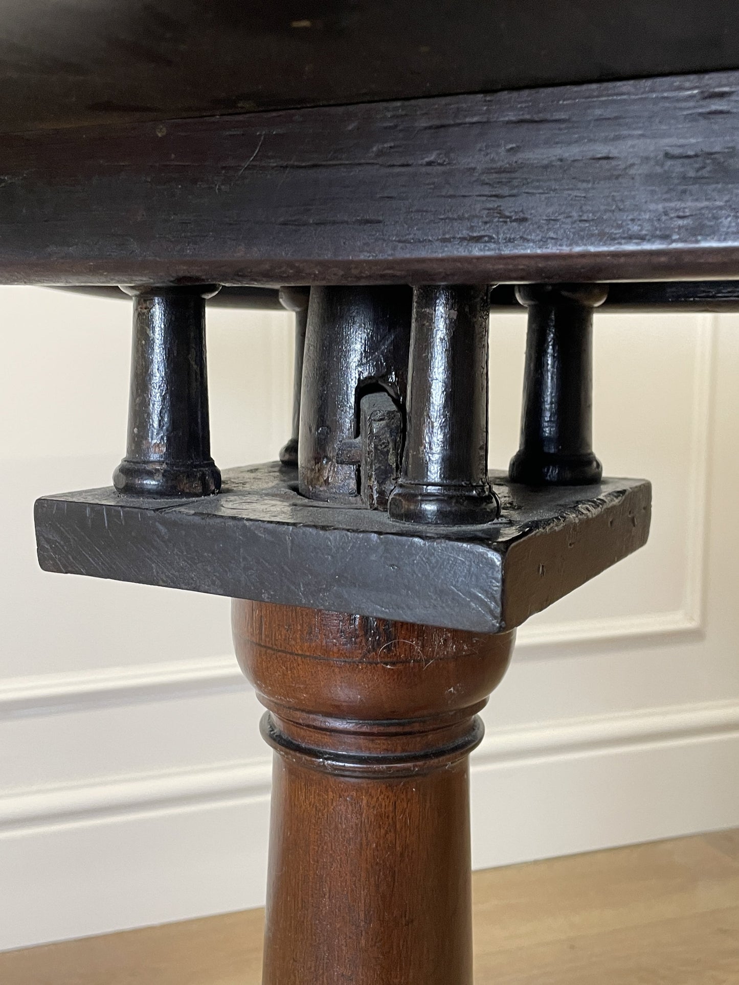 Close-up of a wooden table leg with metal support bracket against a neutral background