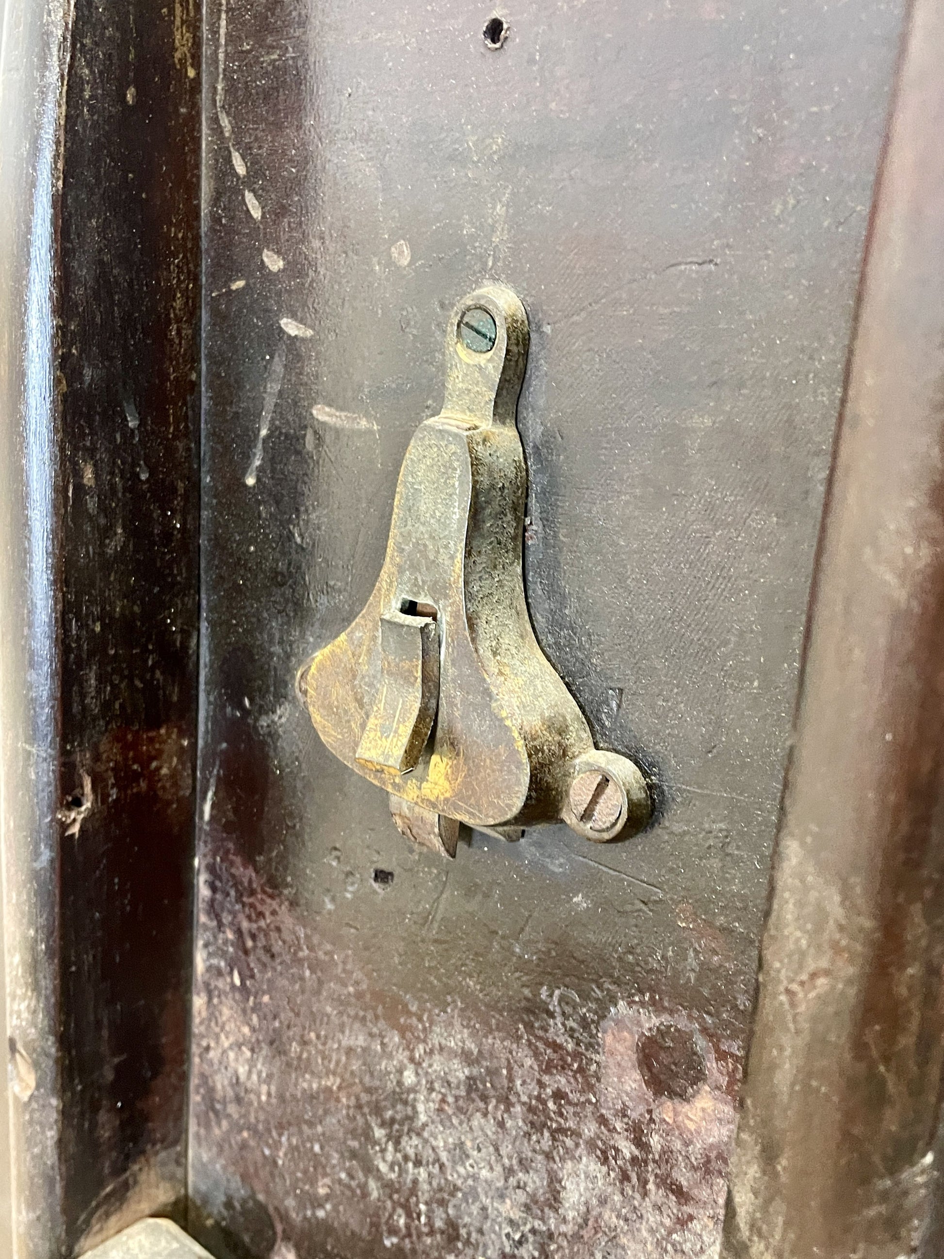 Rust-covered metal object with a small metallic bracket on a textured surface