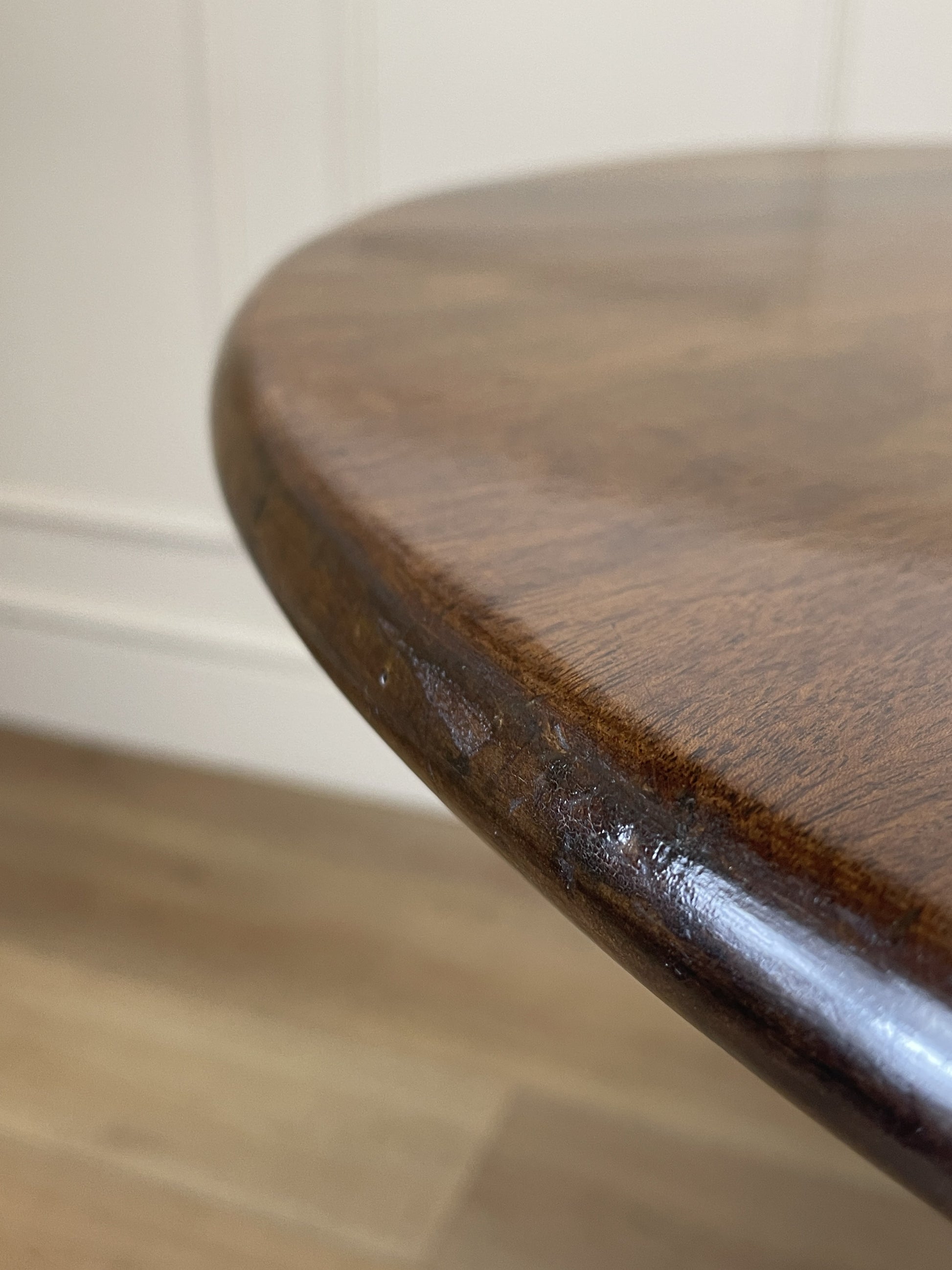 Close-up of a wooden stool with a worn surface on a tiled floor.
