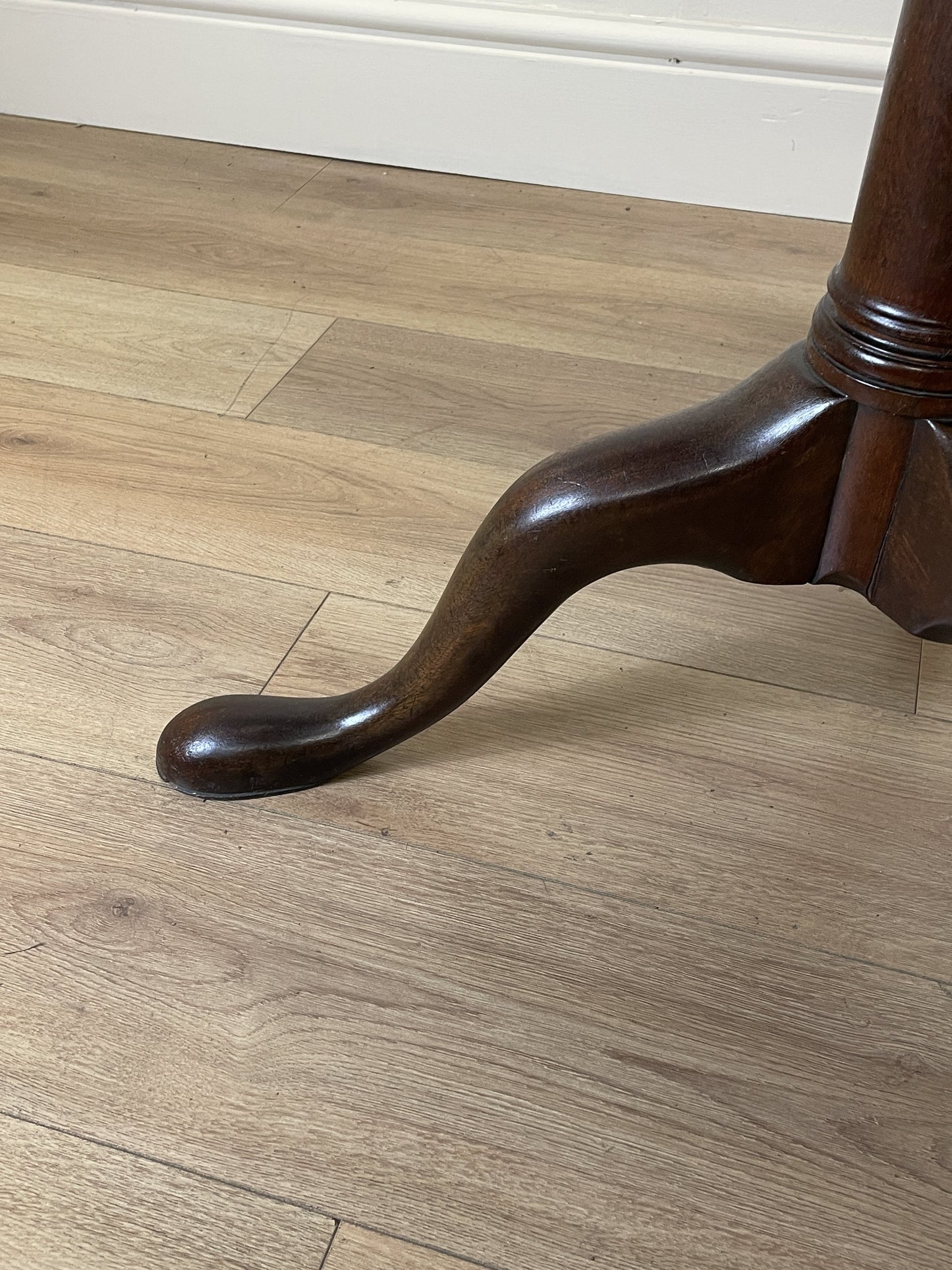 Wooden leg of a piece of furniture on a wooden floor