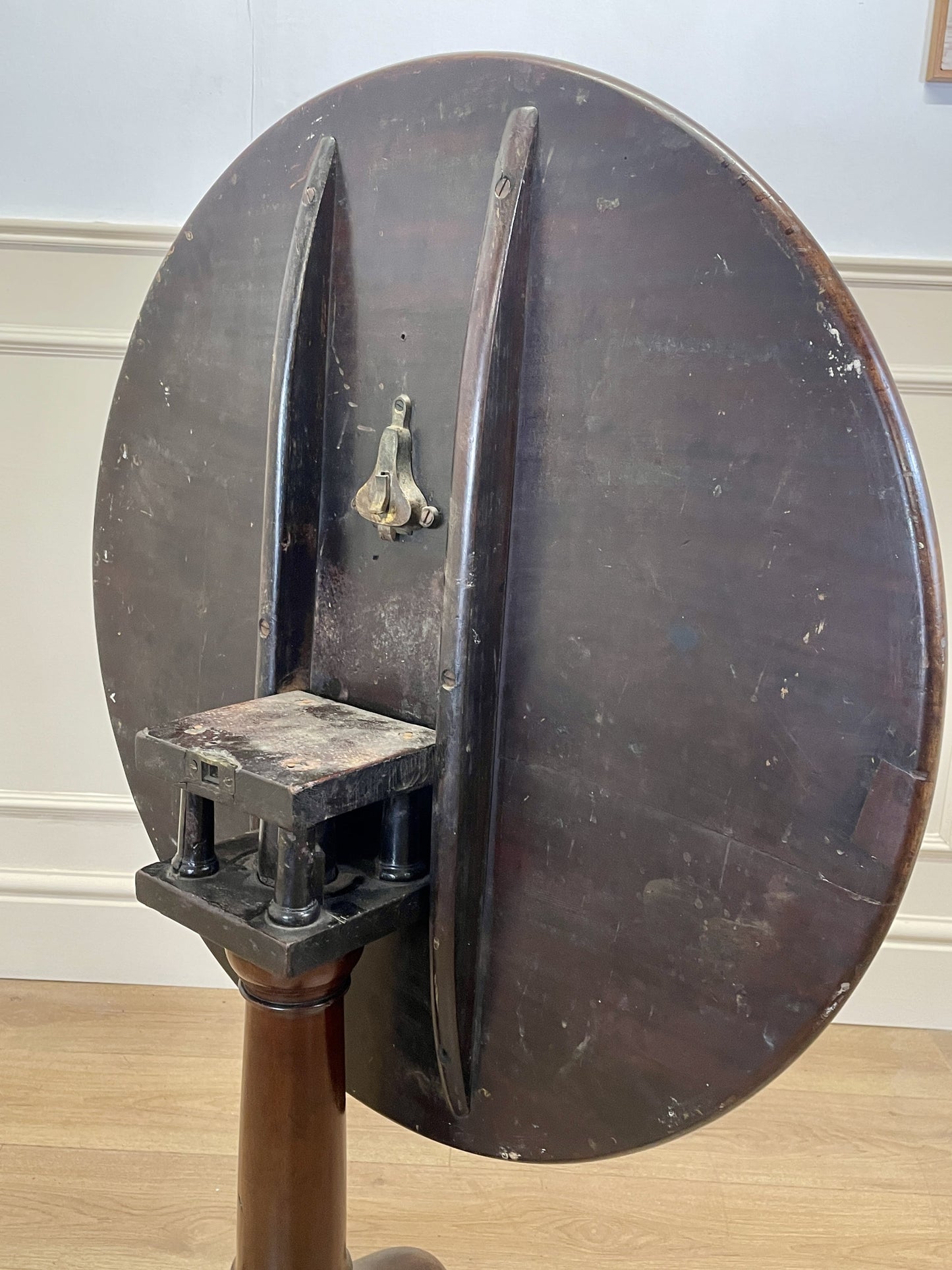 Vintage mechanical device with a large circular component on a wooden floor.
